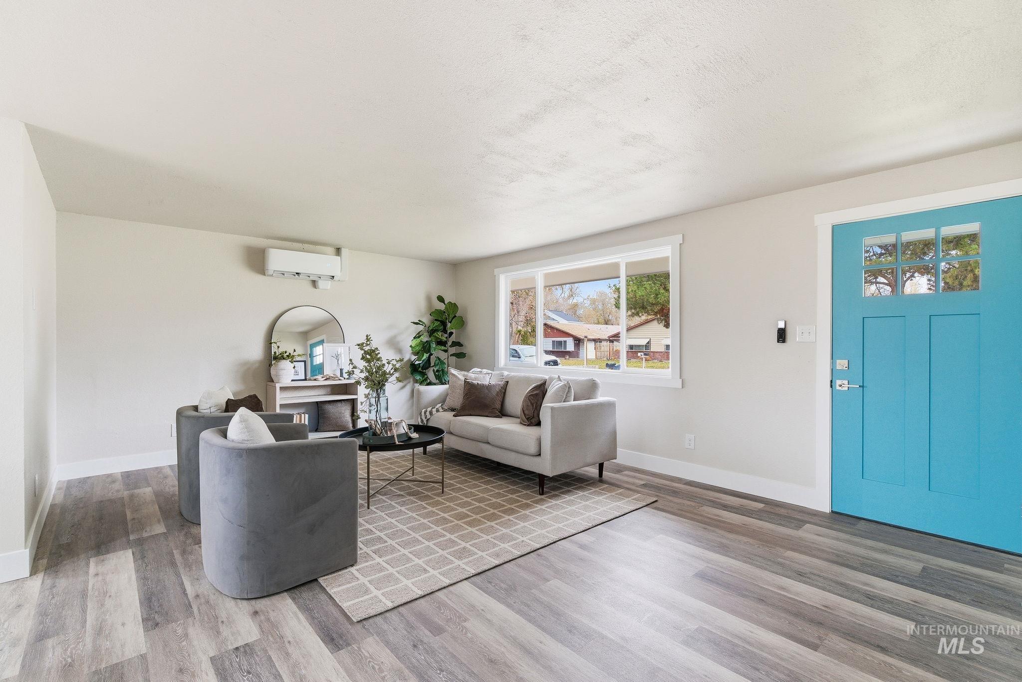 Living area with wood finished floors, a textured ceiling, and a wall mounted AC