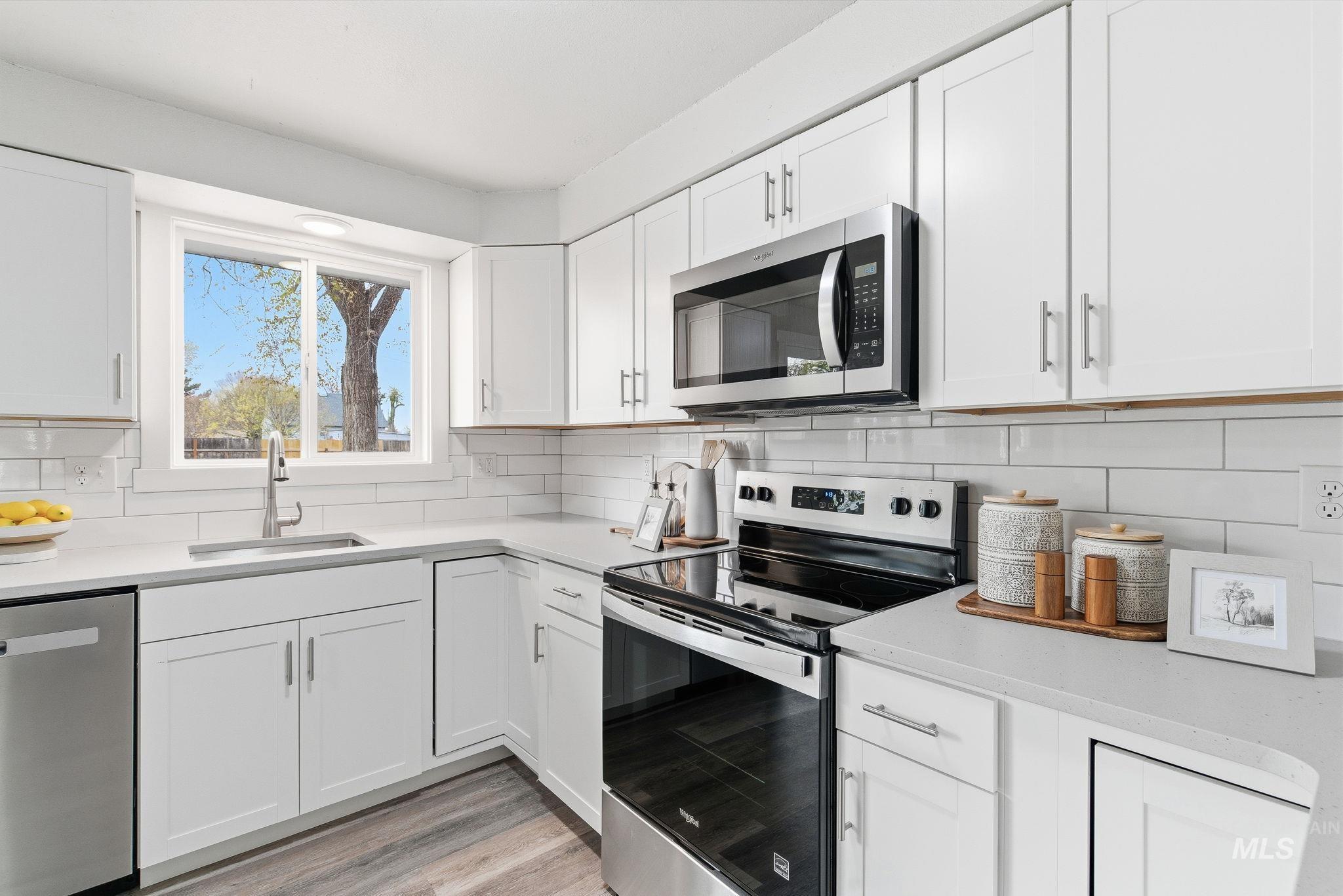 Kitchen featuring stainless steel appliances, white cabinets, and tasteful backsplash
