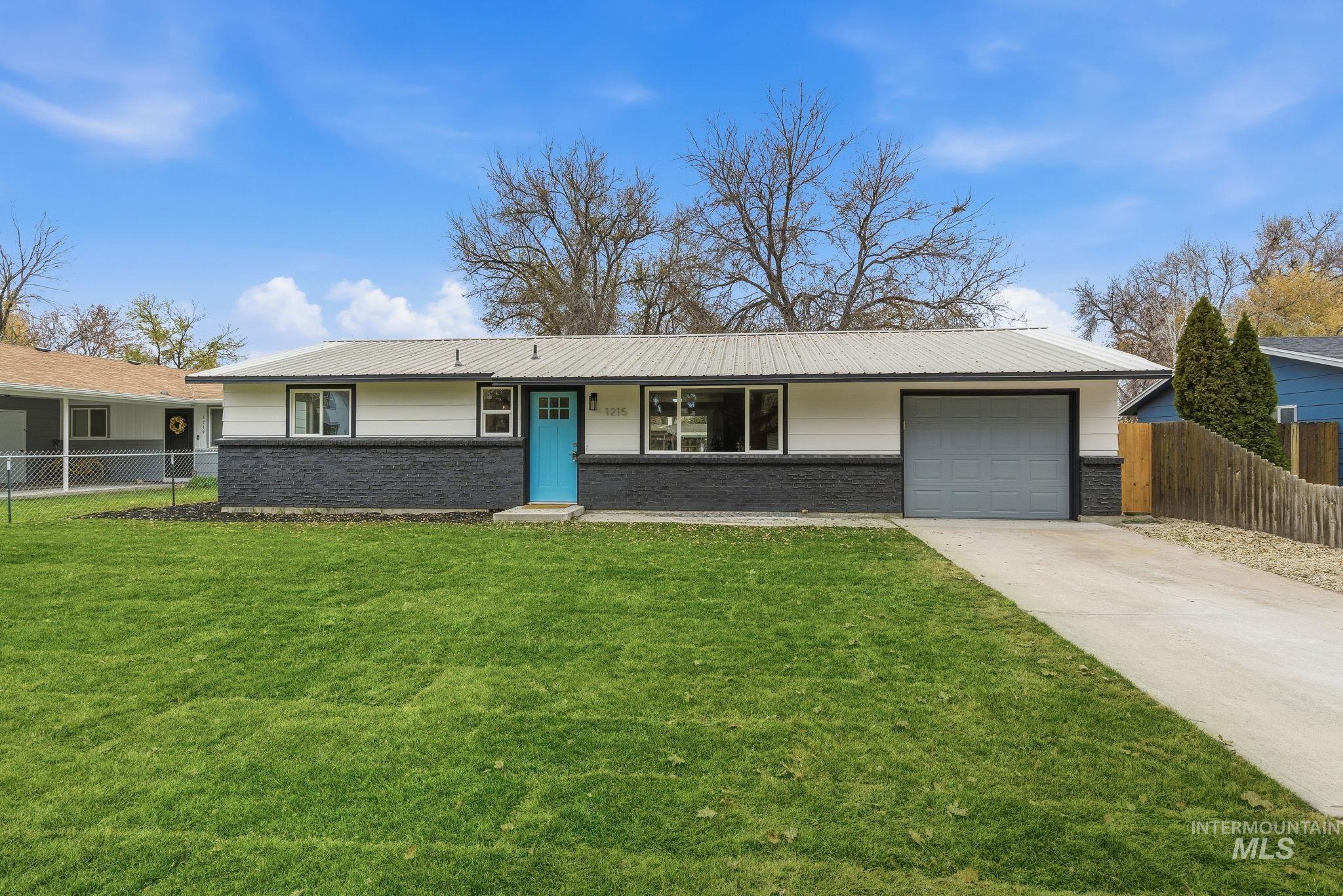 Ranch-style house with brick siding, an attached garage, driveway, and a metal roof