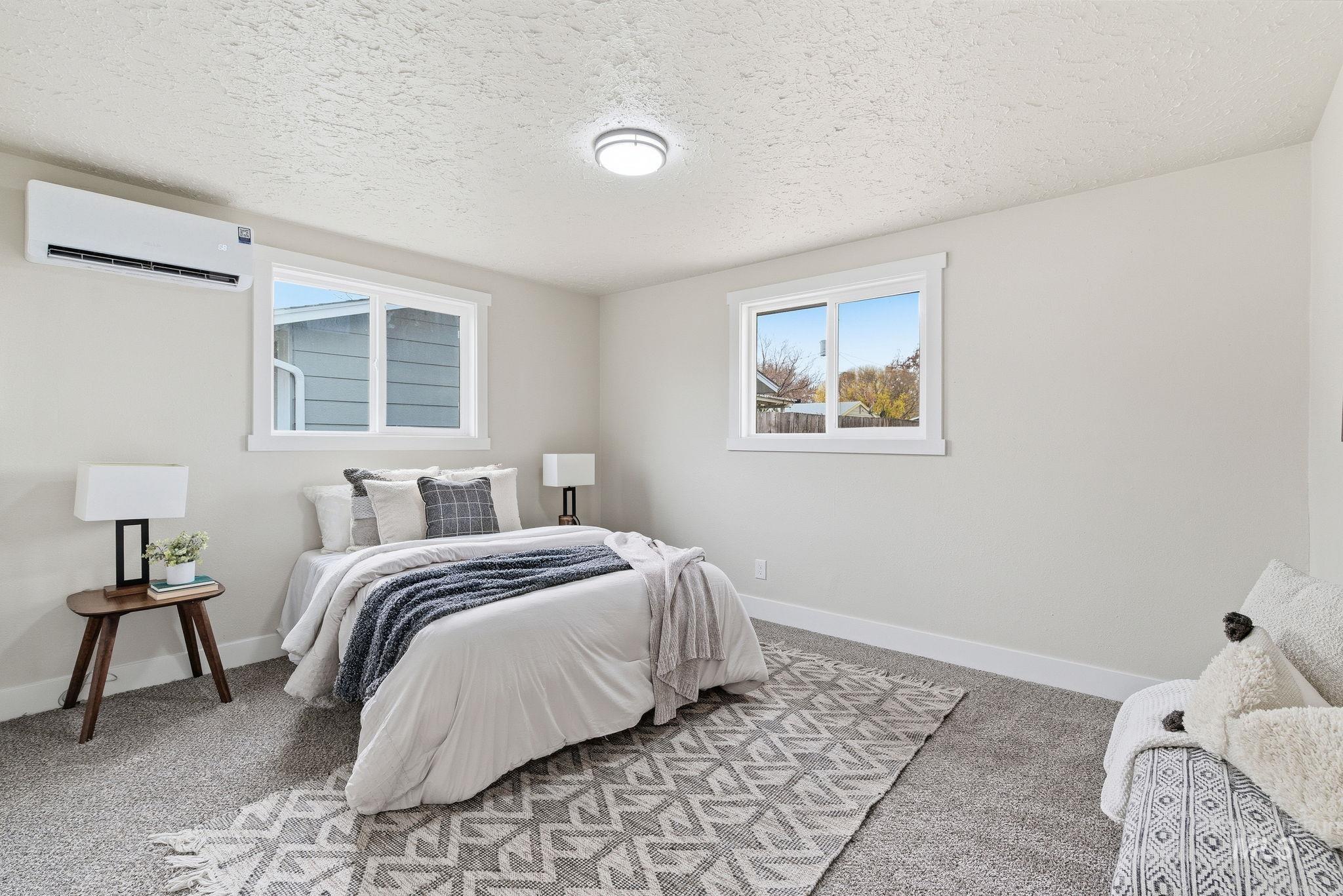 Bedroom featuring carpet flooring, a textured ceiling, and a wall unit AC