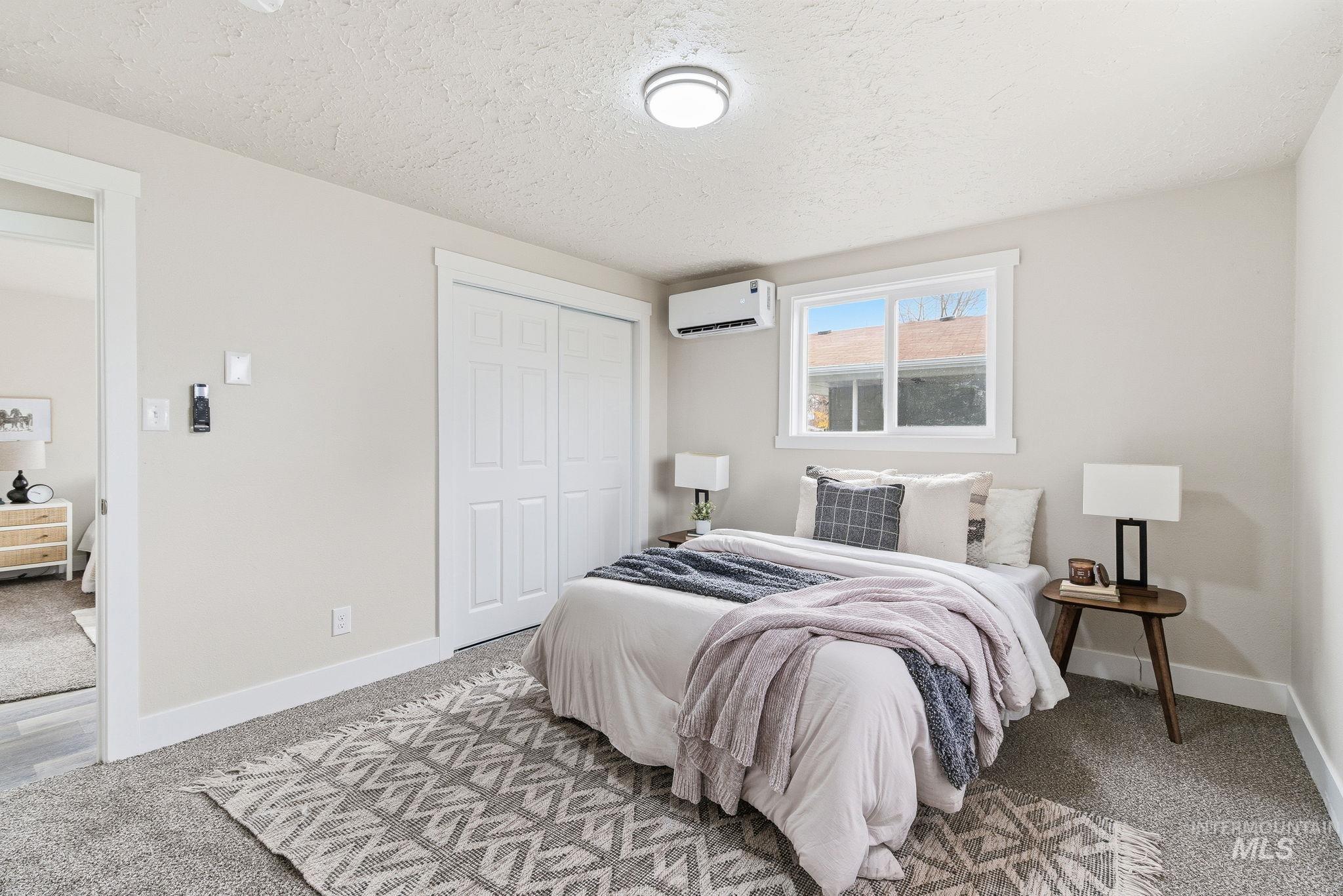 Bedroom featuring carpet, a closet, a textured ceiling, and a wall unit AC