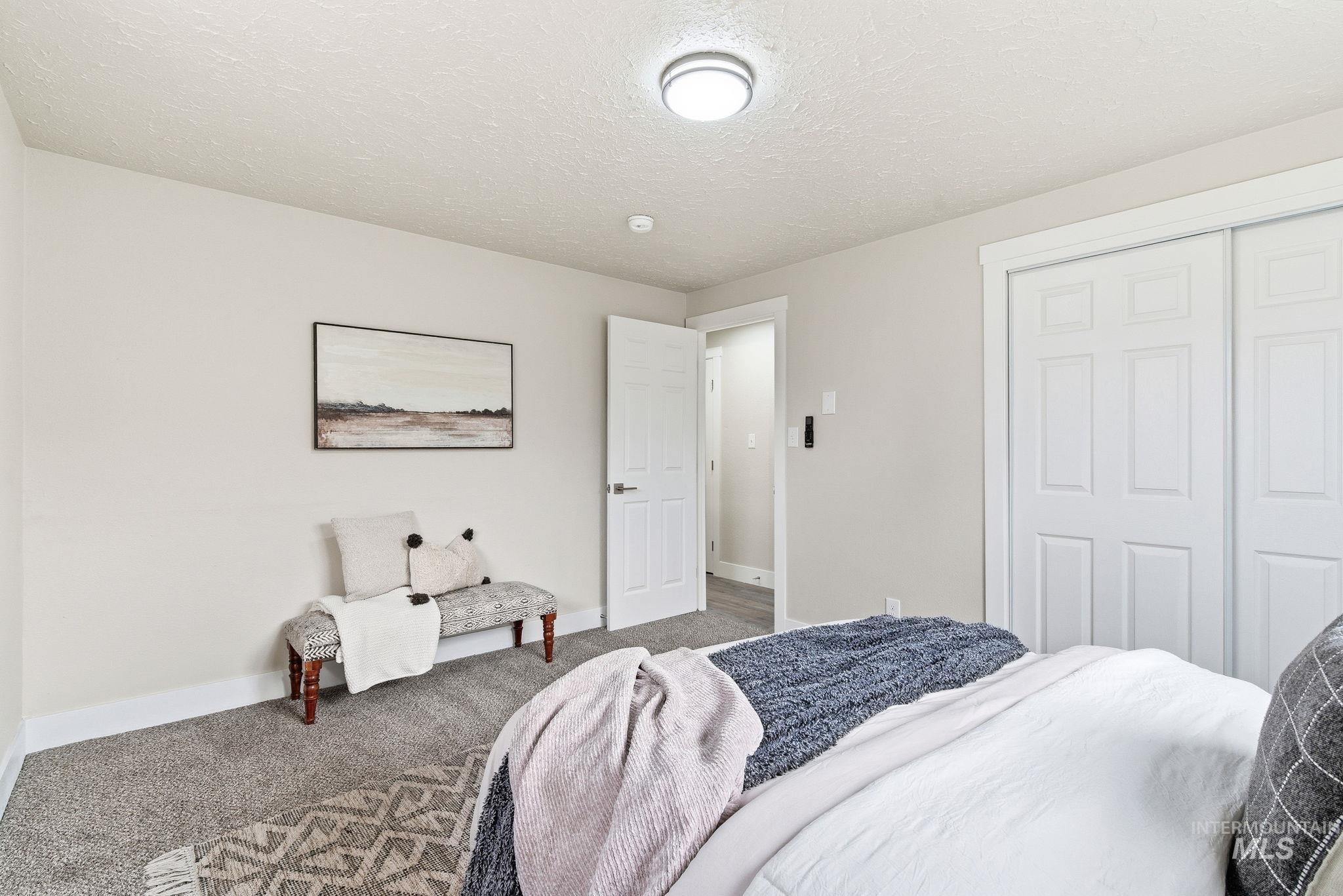 Carpeted bedroom with a textured ceiling and a closet