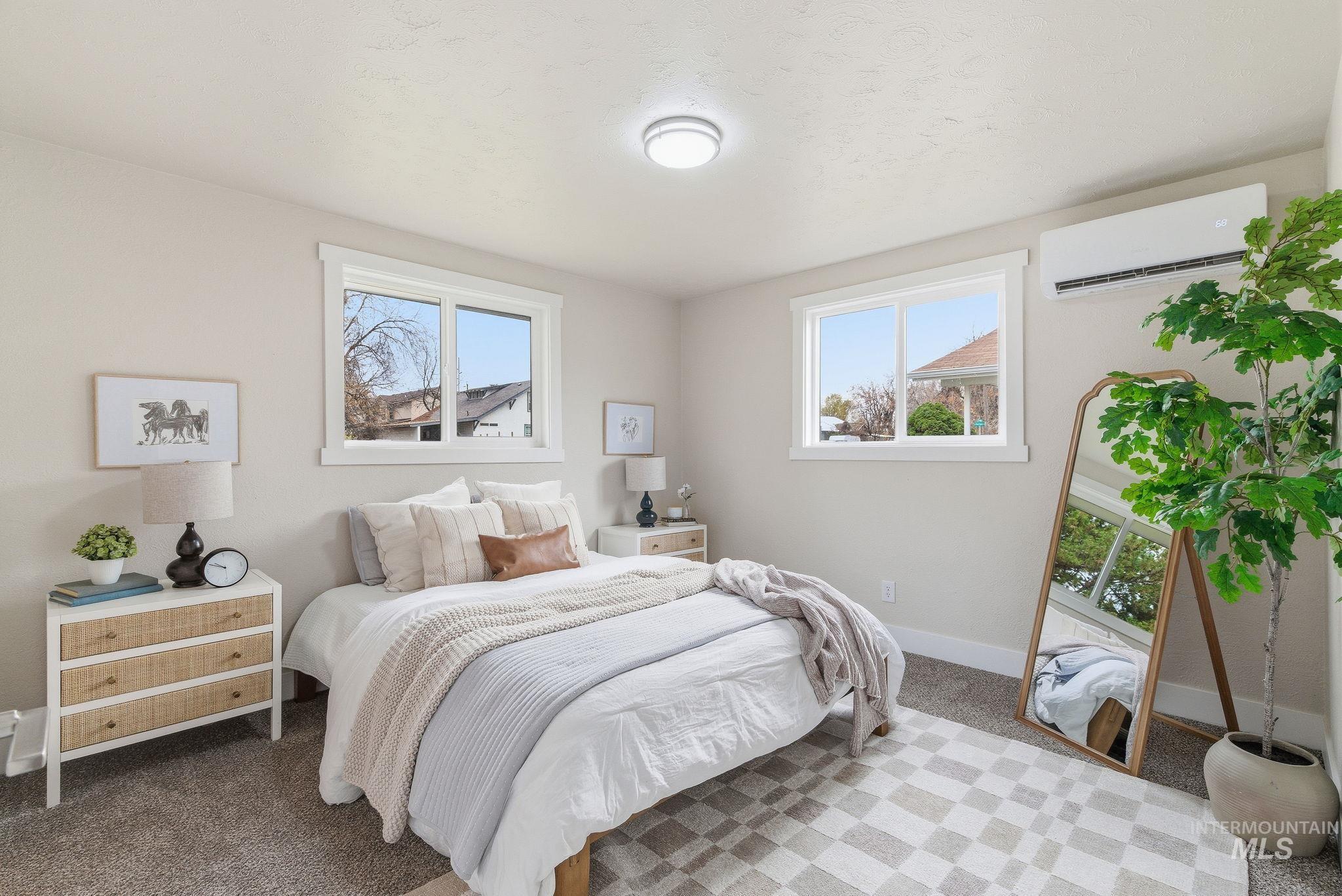 Carpeted bedroom featuring baseboards and a wall mounted air conditioner