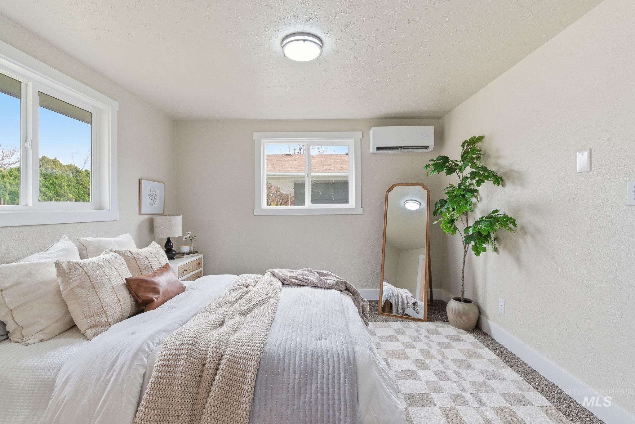 Carpeted bedroom featuring baseboards and an AC wall unit