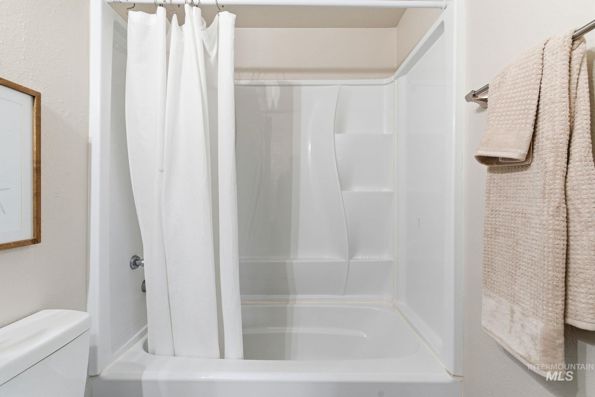 Bathroom featuring shower / bathtub combination with curtain and a textured wall