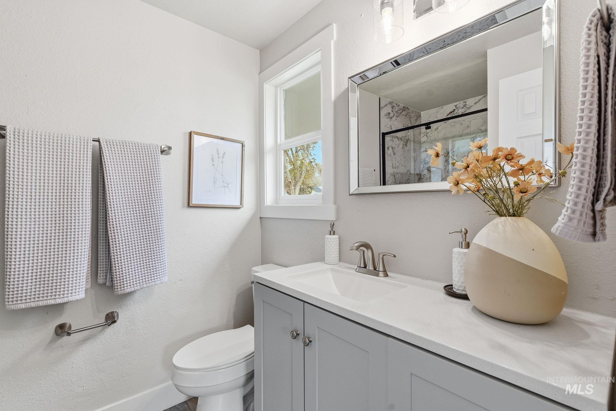 Full bath with a textured wall, a marble finish shower, and vanity