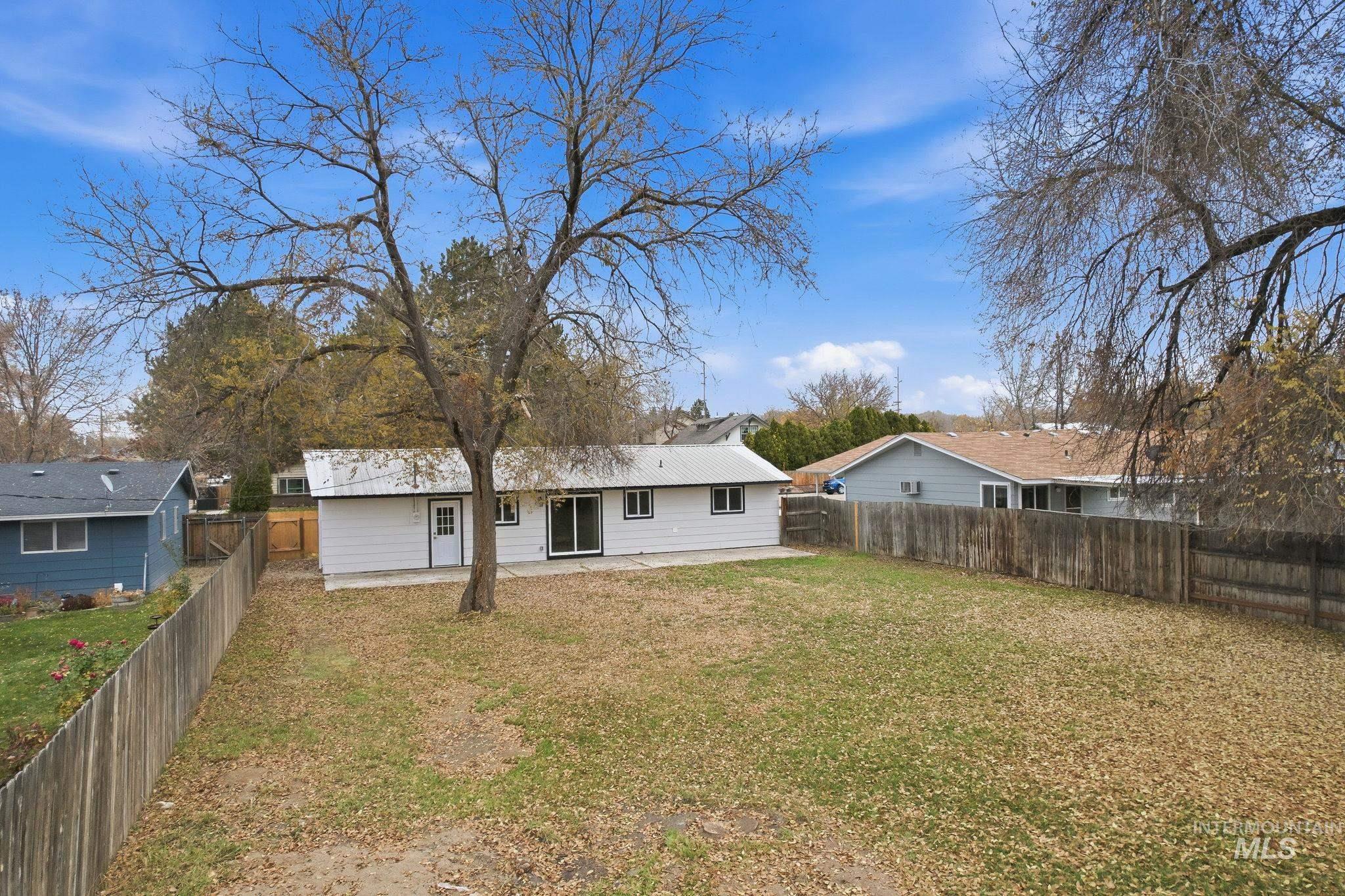 Rear view of house featuring a patio area, a fenced backyard, and a metal roof