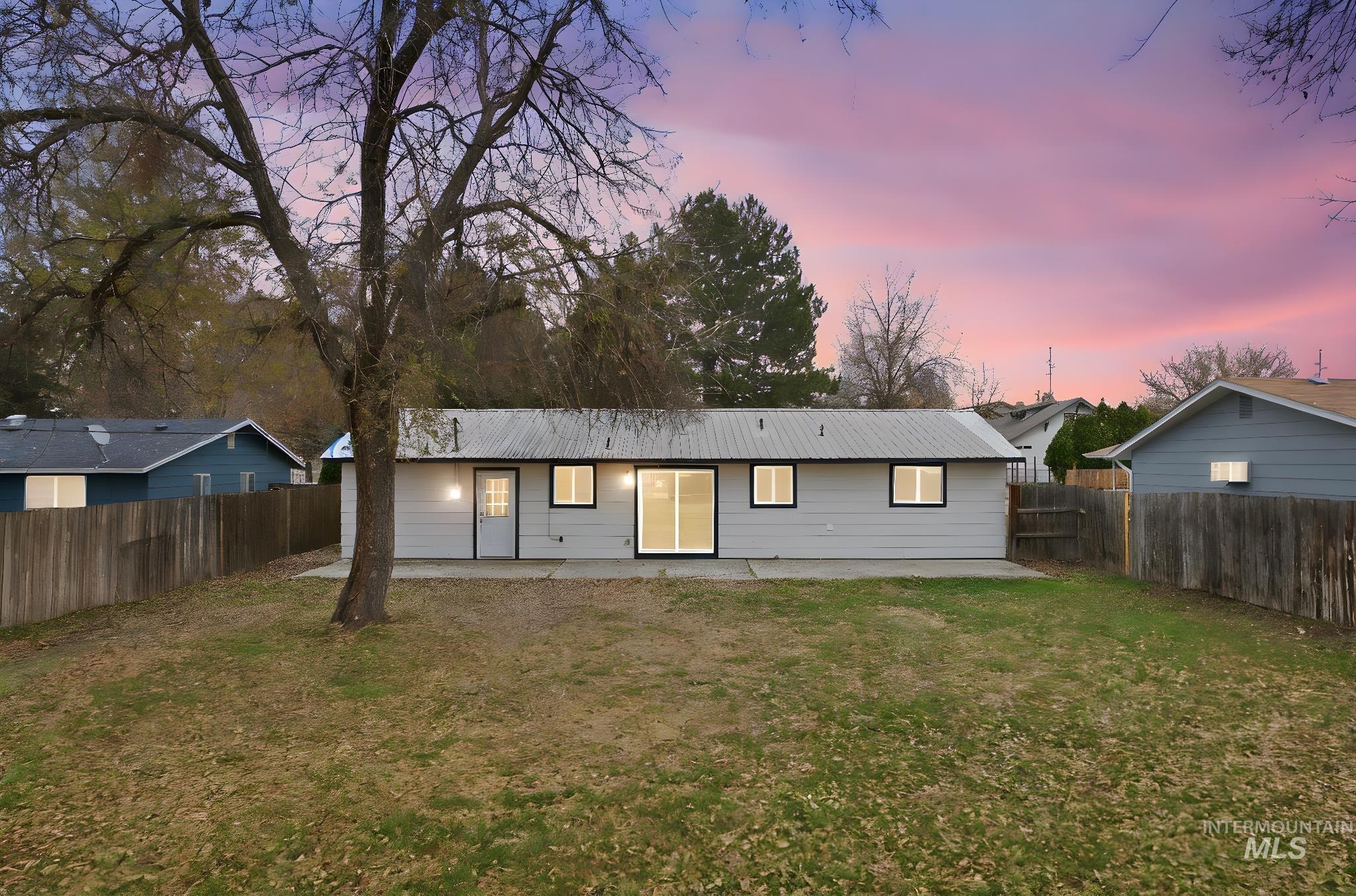 Back of property with a patio area, a metal roof, and a fenced backyard