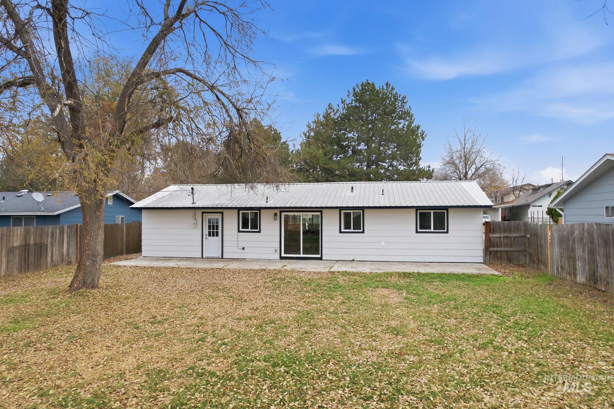 Rear view of property with a patio, a metal roof, and a fenced backyard