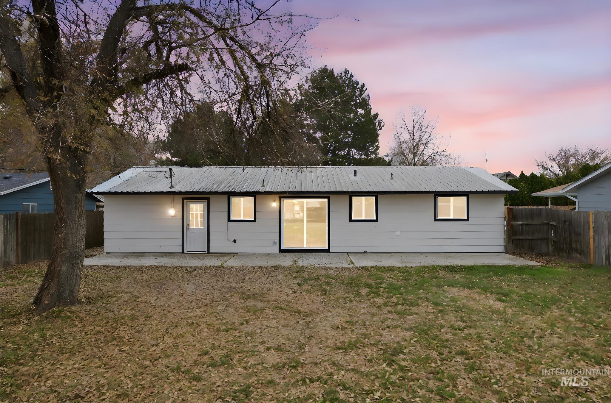 Back of house with a patio, a fenced backyard, and a metal roof