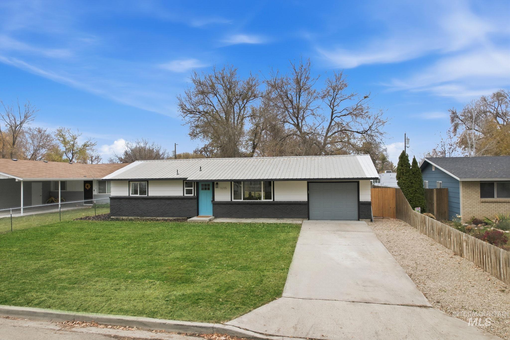 Single story home featuring concrete driveway, brick siding, a metal roof, and an attached garage