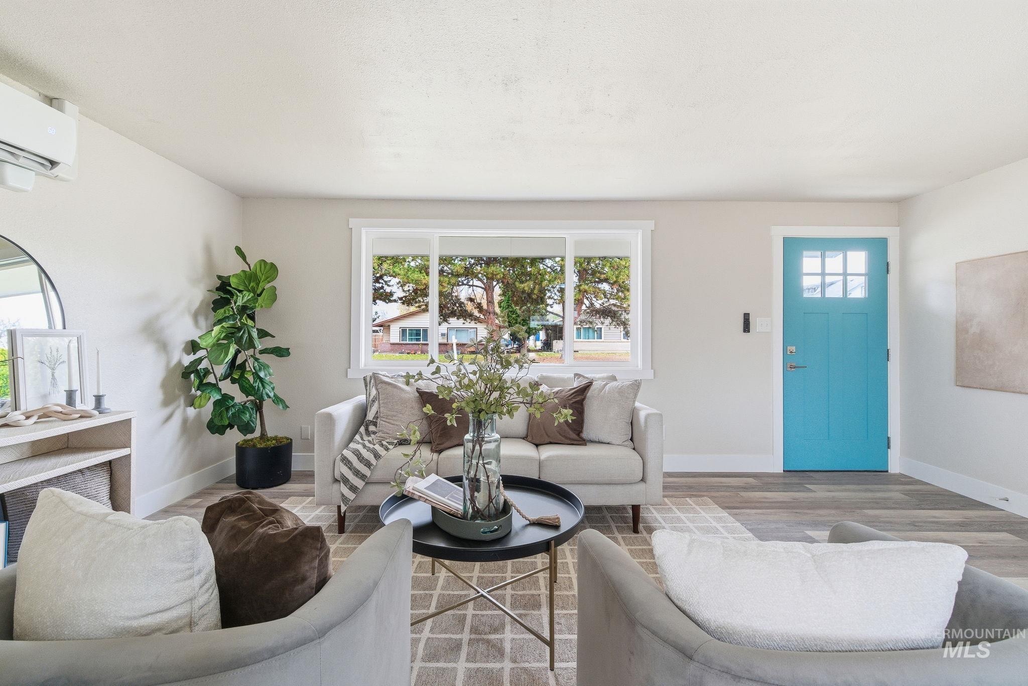 Living room featuring plenty of natural light, wood finished floors, and a wall unit AC