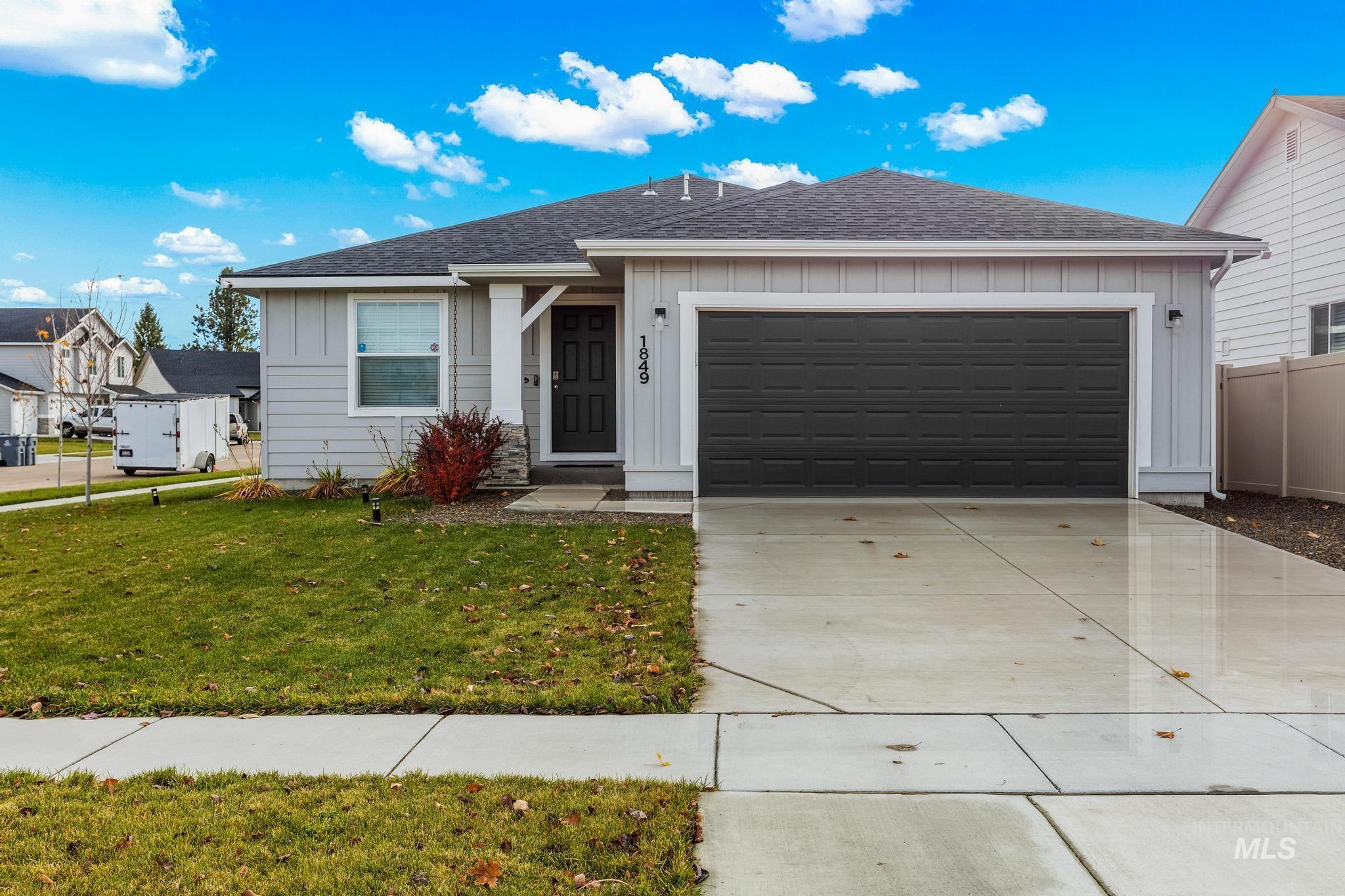 Single story home featuring board and batten siding, roof with shingles, an attached garage, and driveway