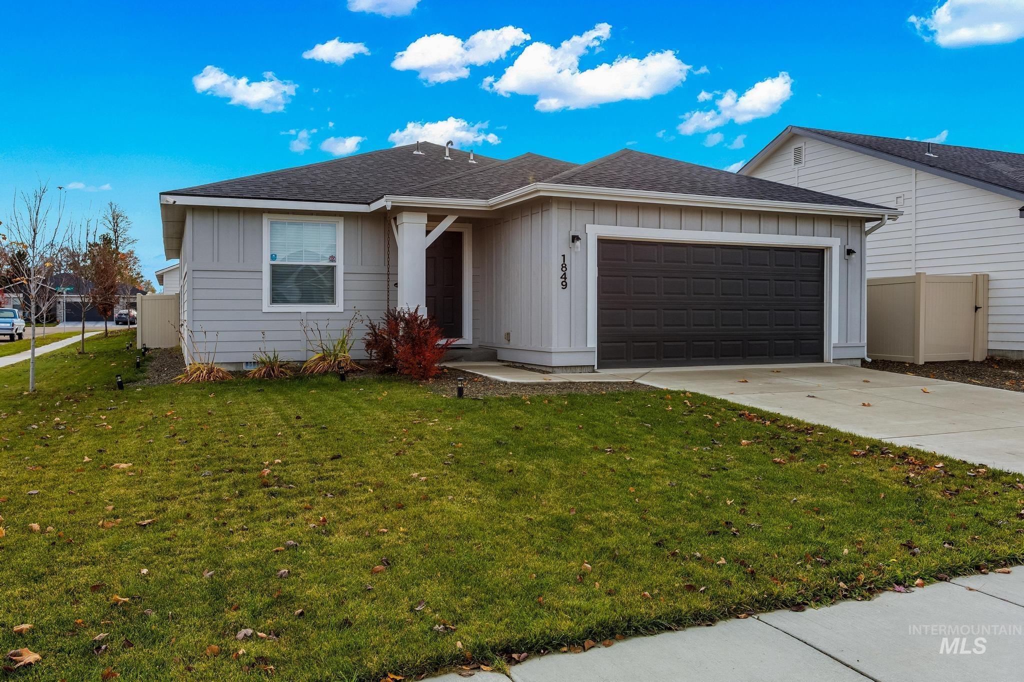 Single story home featuring a shingled roof, board and batten siding, an attached garage, and concrete driveway
