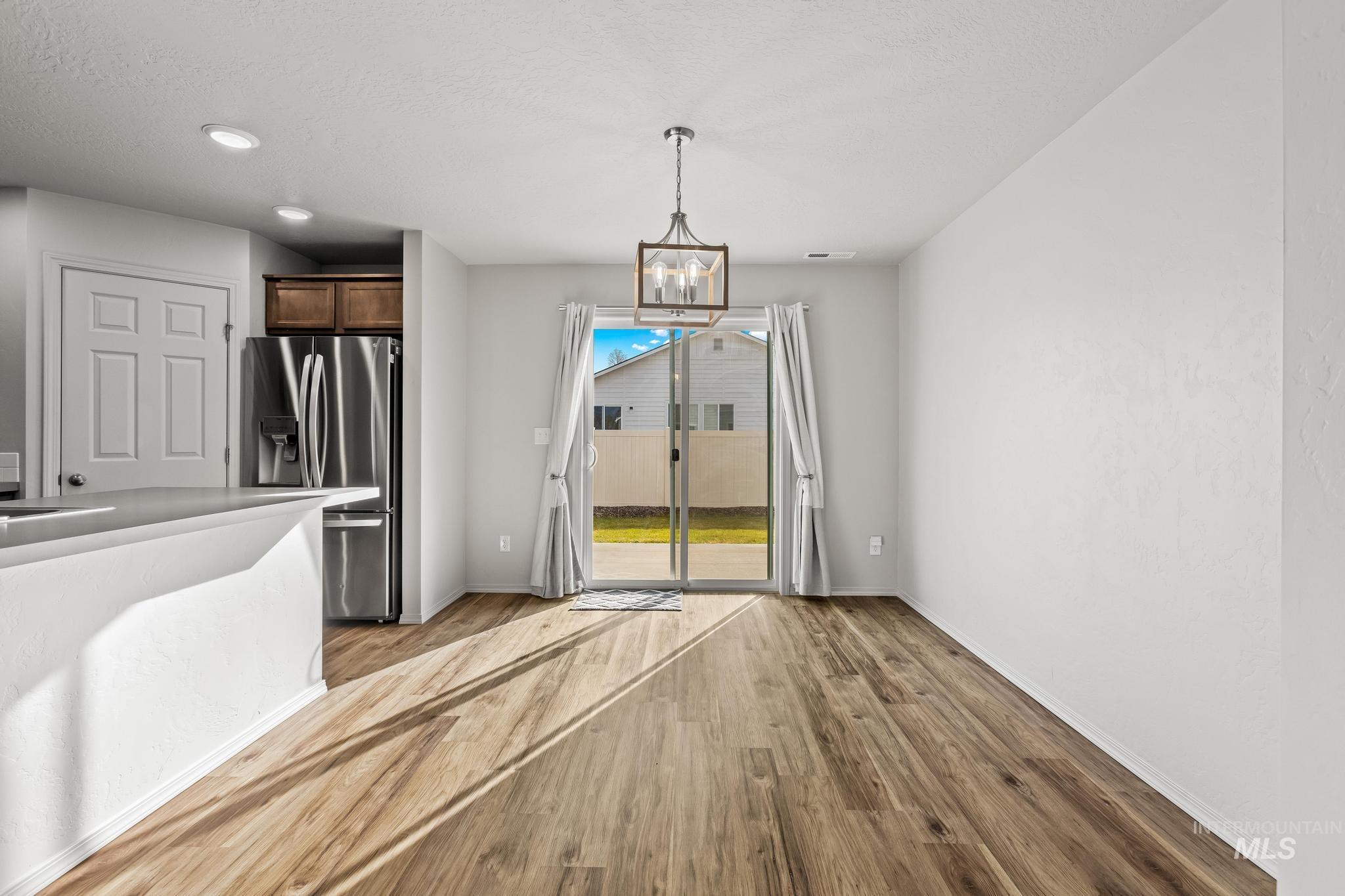 Unfurnished dining area with light wood-type flooring, a chandelier, recessed lighting, and a textured ceiling
