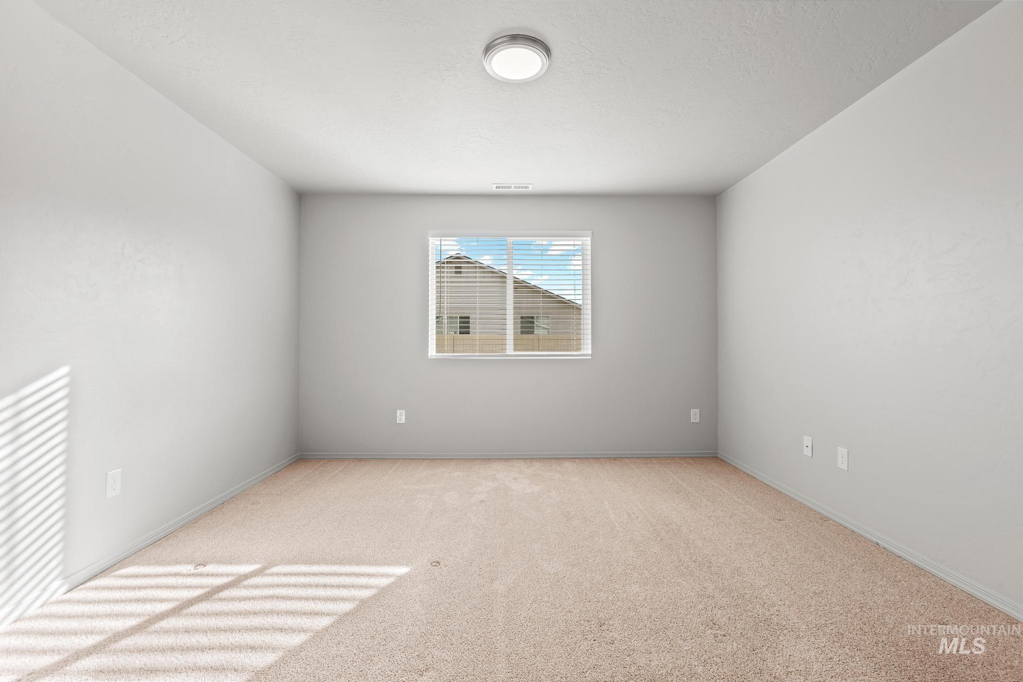 Unfurnished room featuring light carpet and baseboards