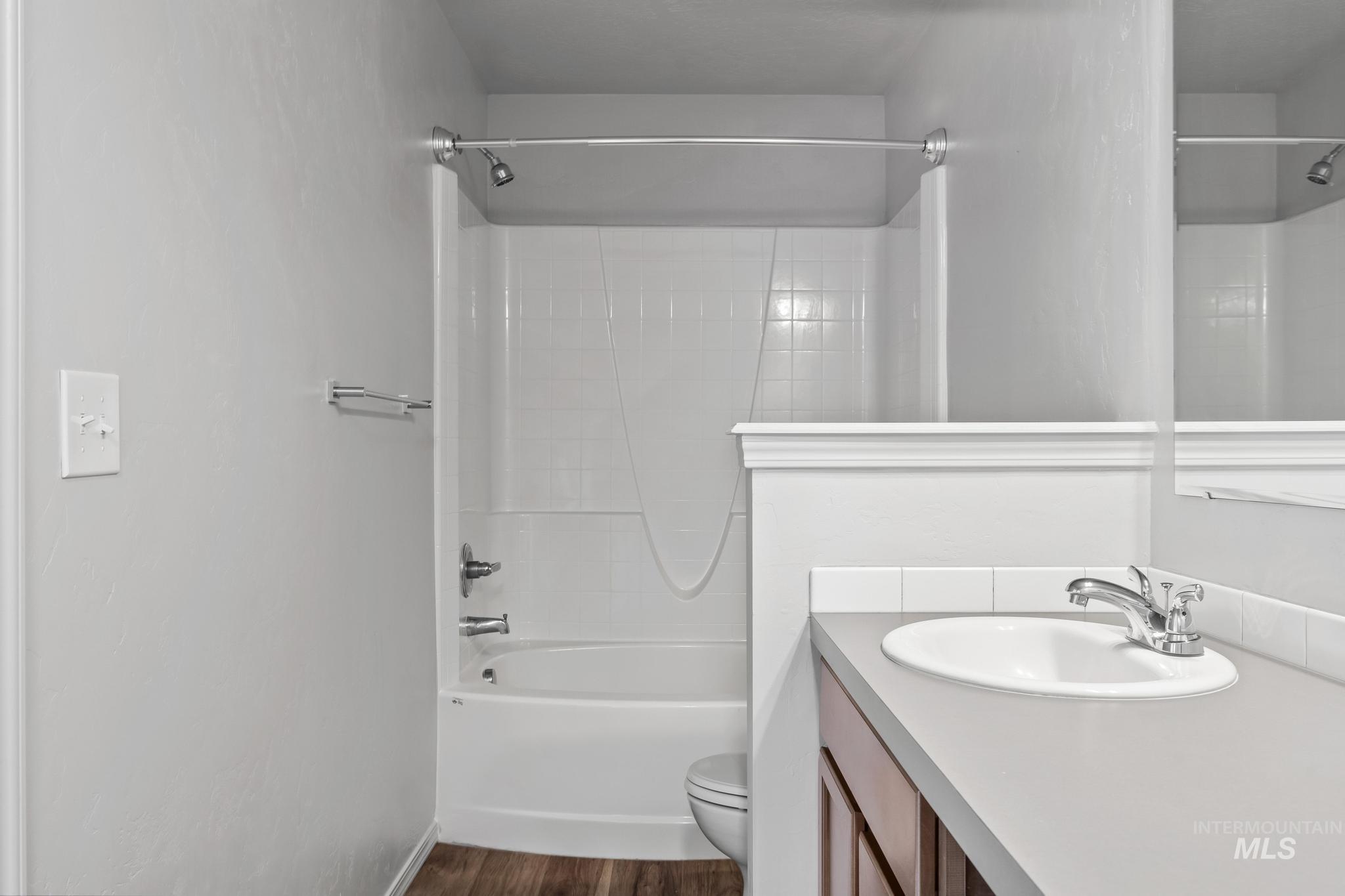 Bathroom featuring shower / washtub combination, vanity, and dark wood-type flooring