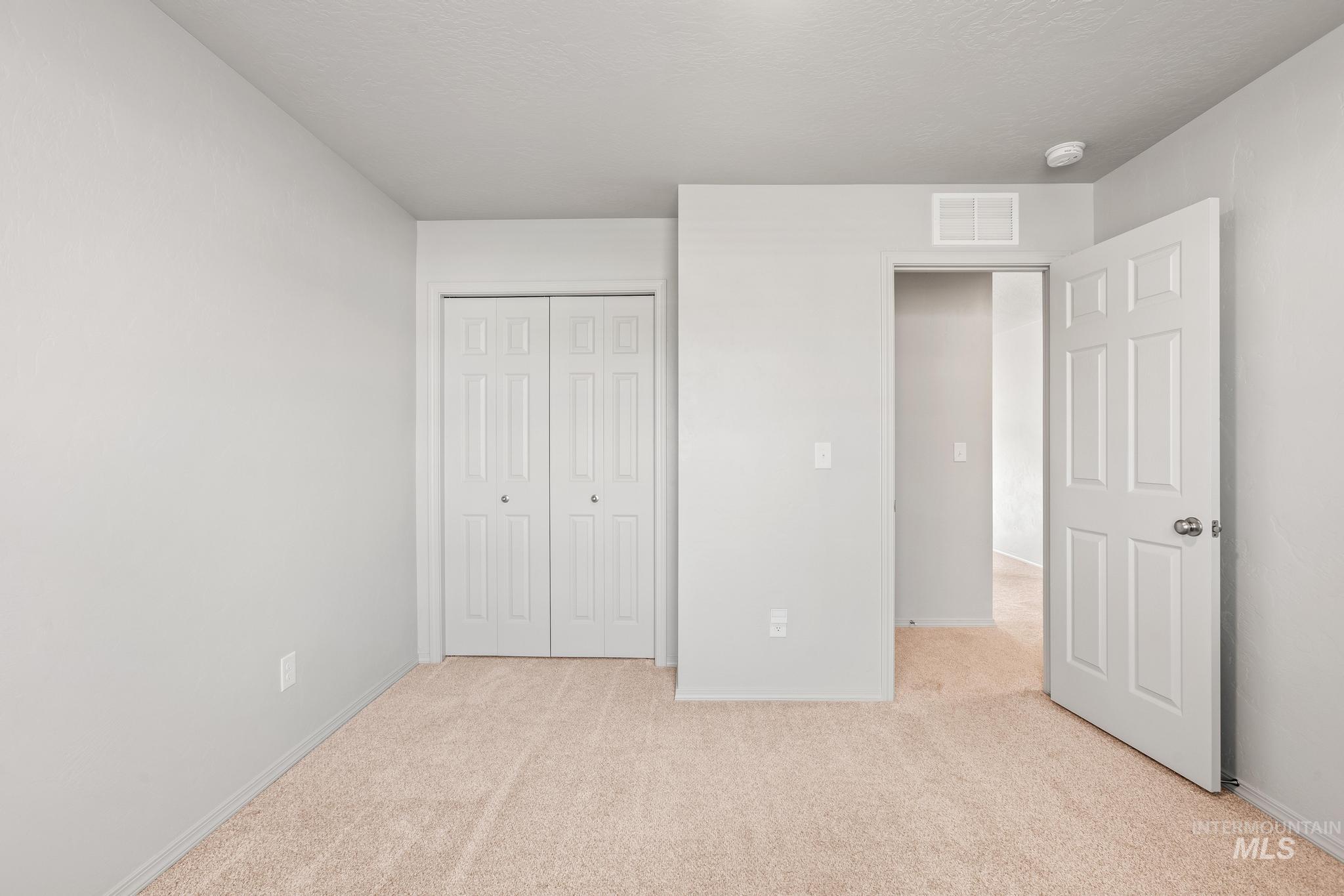 Unfurnished bedroom with light carpet and a closet