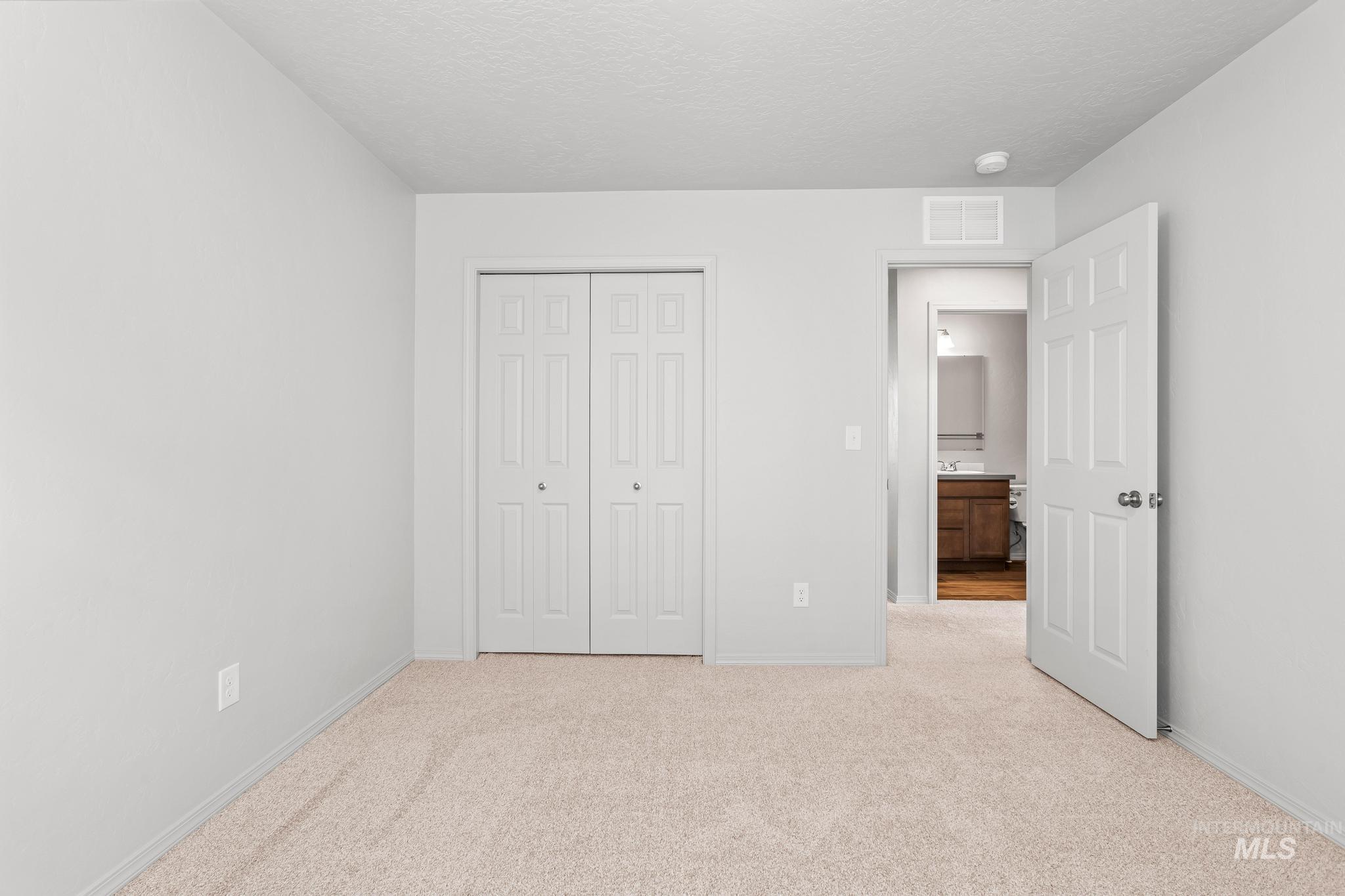 Unfurnished bedroom with light carpet, a closet, and a textured ceiling