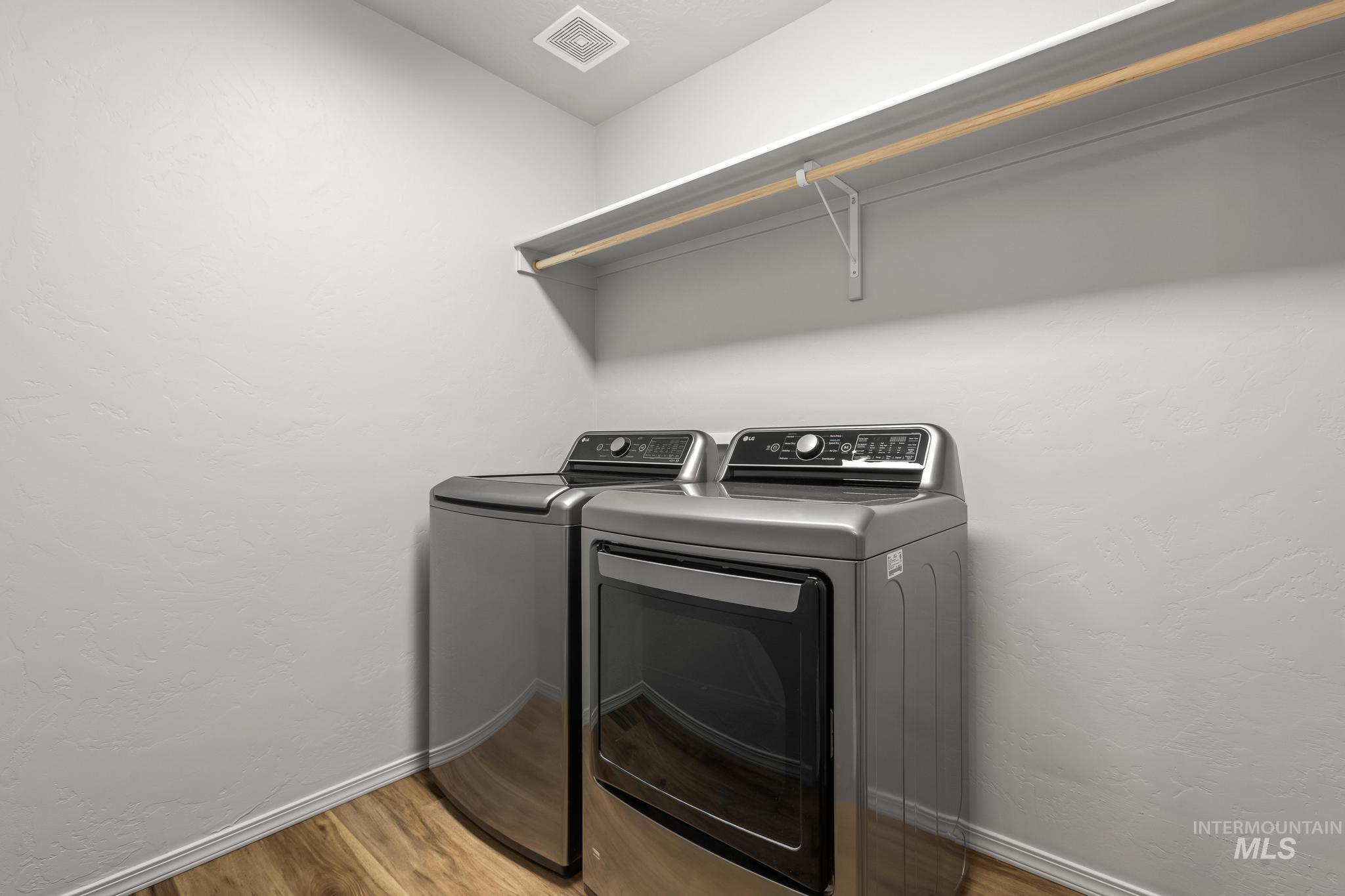 Laundry room with a textured wall, light wood-type flooring, and separate washer and dryer