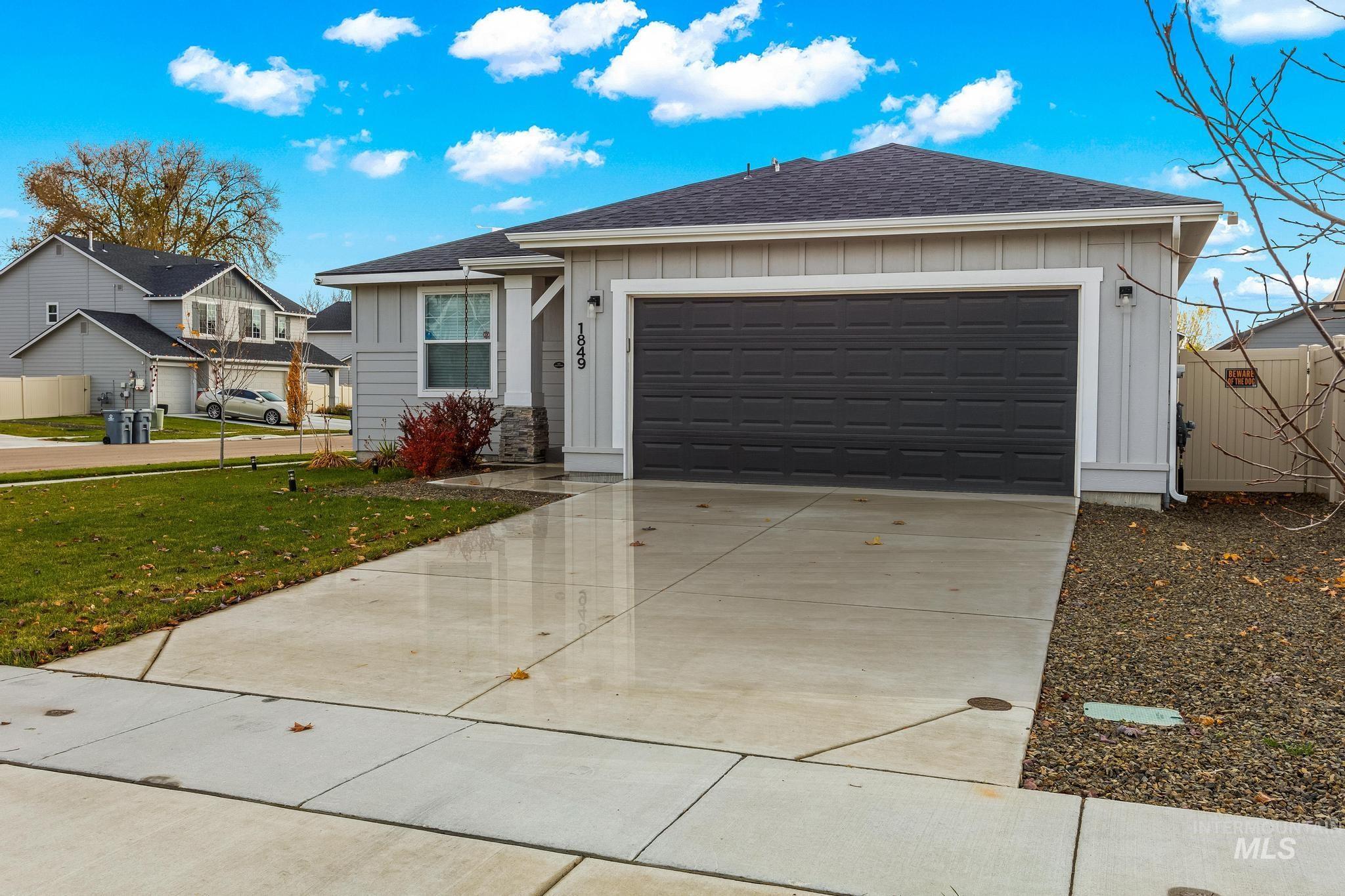 Single story home with board and batten siding, roof with shingles, driveway, and a front lawn