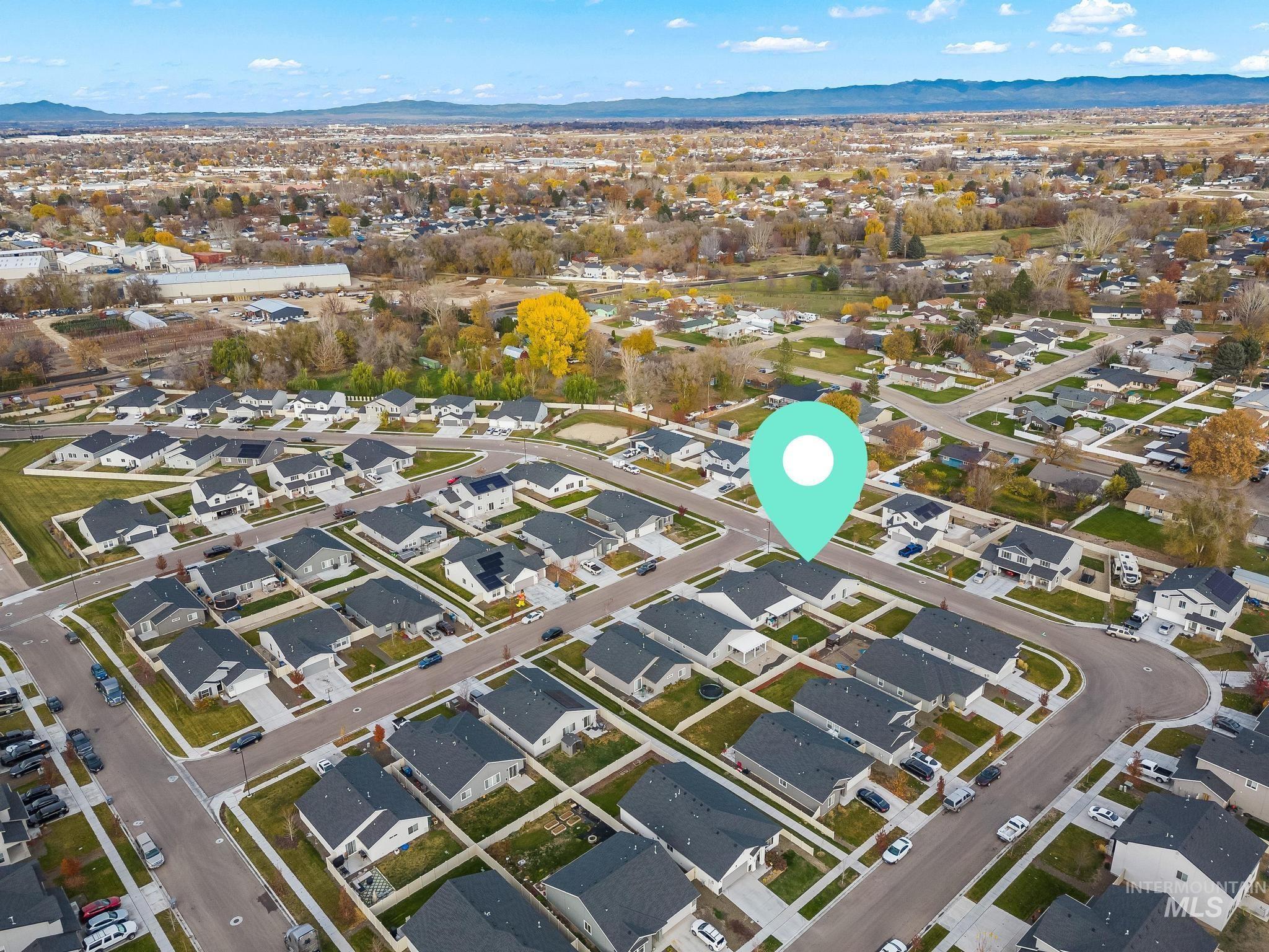 Aerial view of property and surrounding area with nearby suburban area and a mountainous background