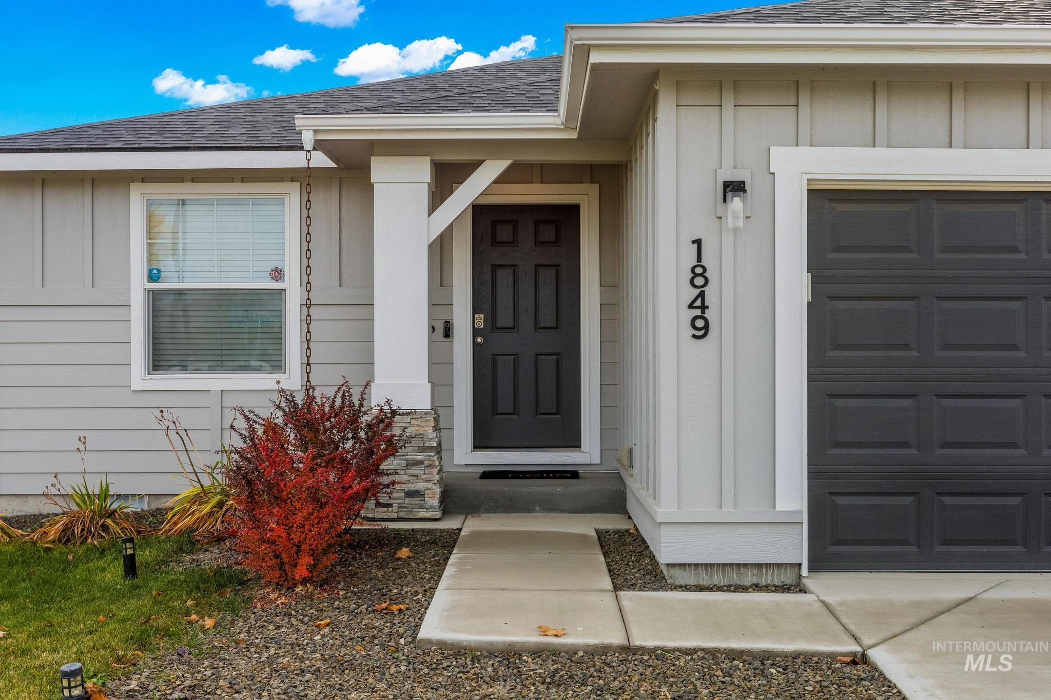 View of exterior entry featuring board and batten siding, roof with shingles, and a garage