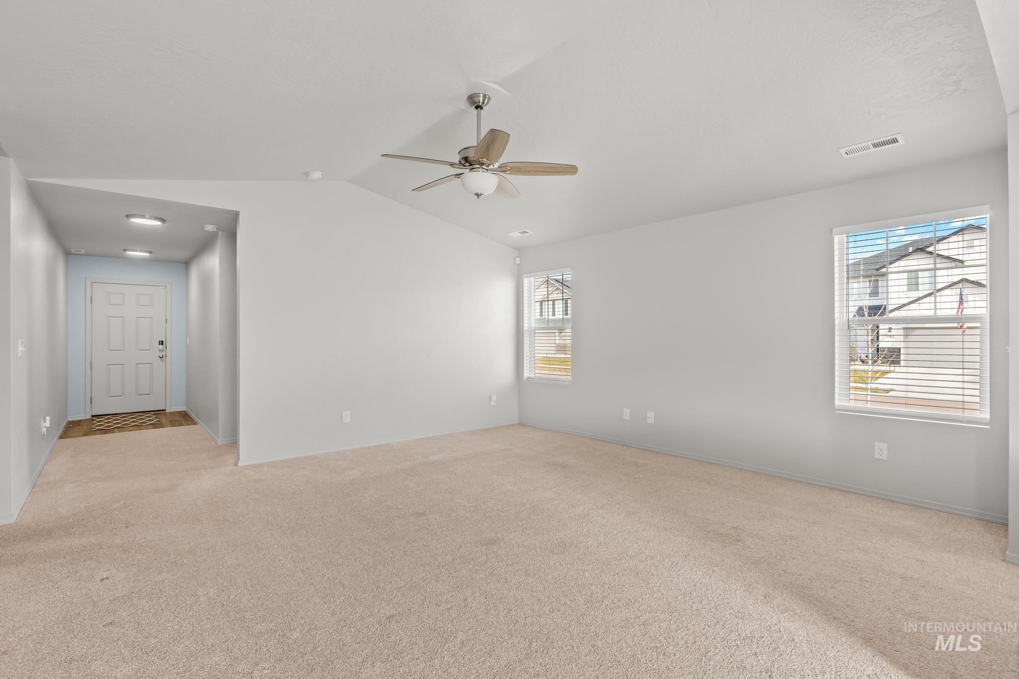 Spare room with light carpet, lofted ceiling, and ceiling fan