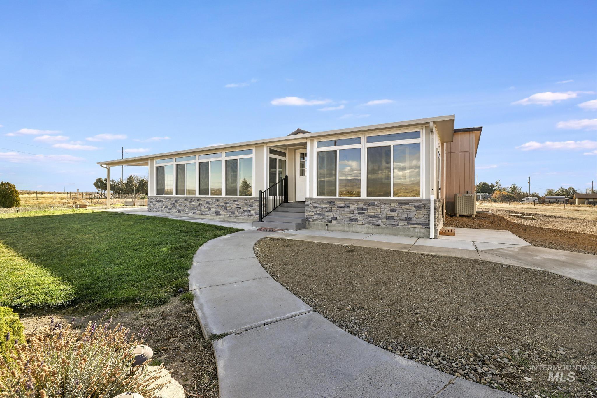 Front of house featuring stone siding, a yard, and entry steps