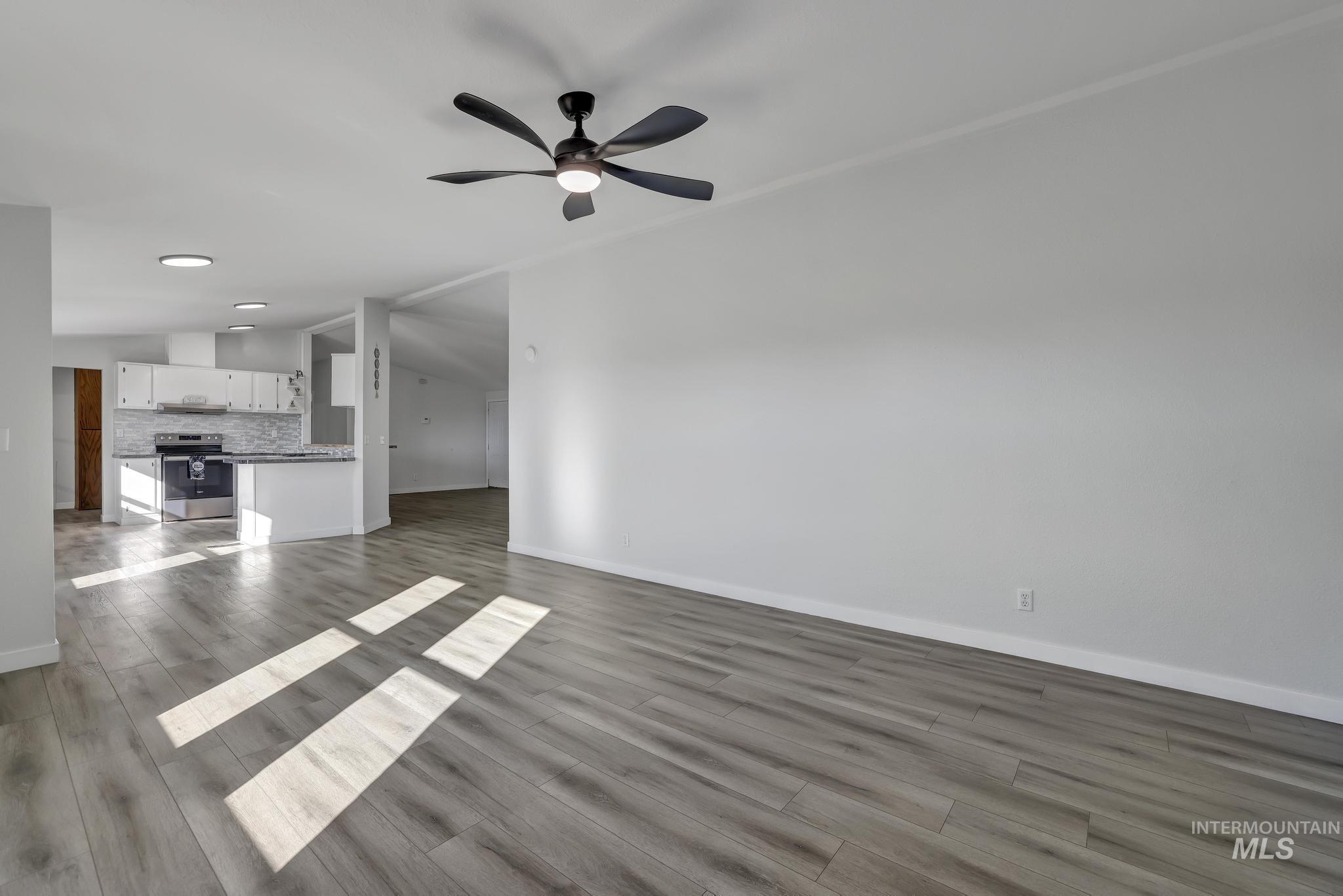 Unfurnished family room featuring dark wood finished floors, a ceiling fan, and vaulted ceiling