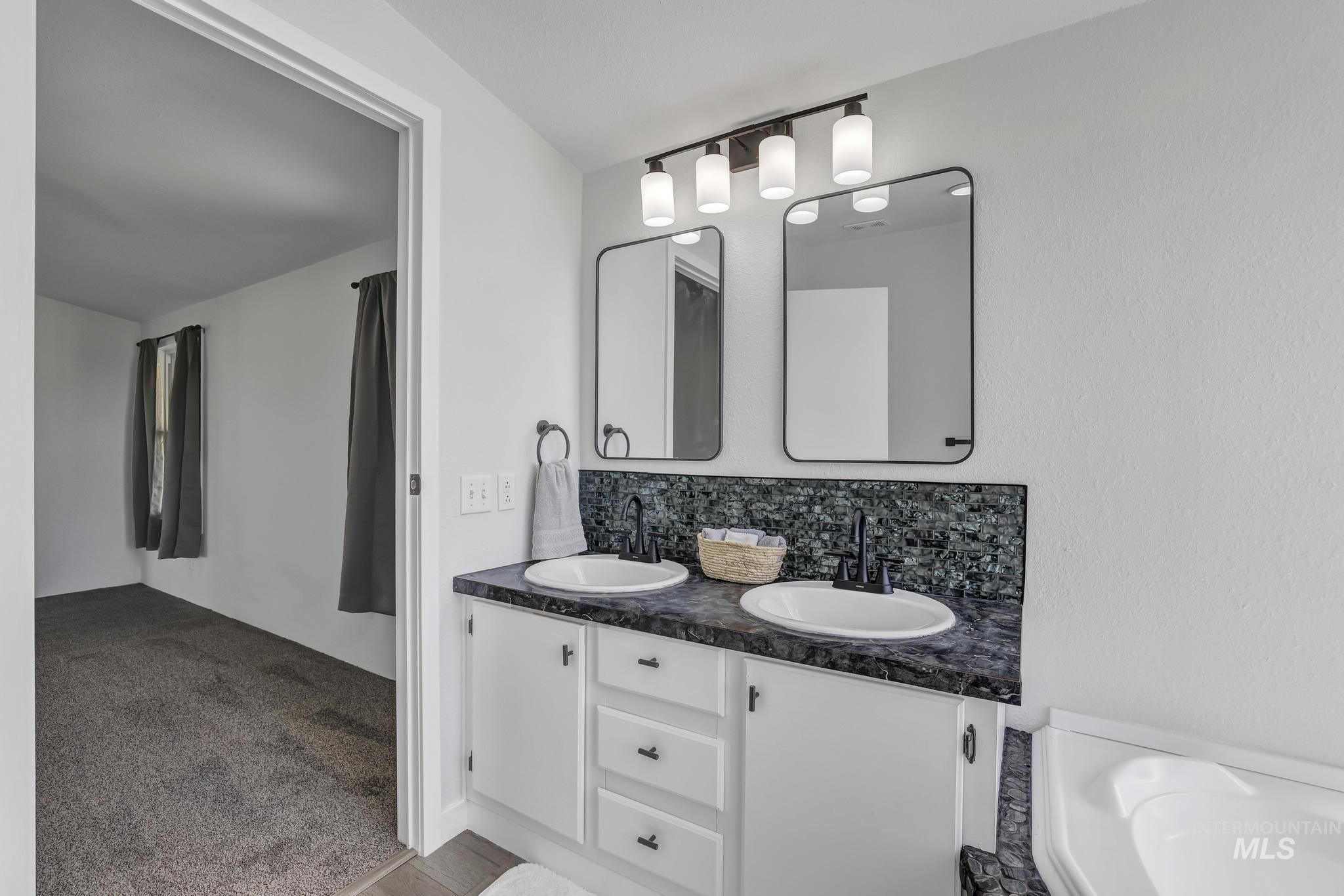 Full bath featuring backsplash, double vanity, and light colored carpet