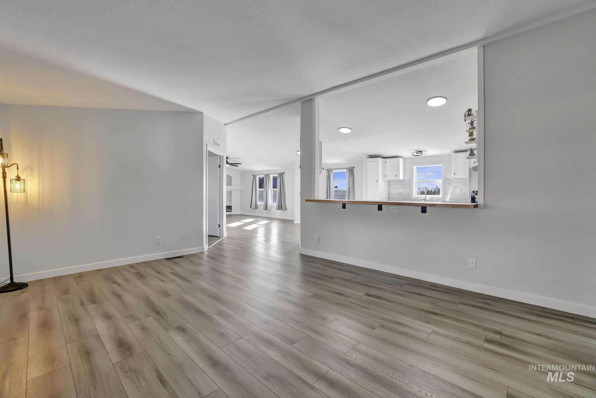 Unfurnished living room featuring light wood-style flooring and baseboards