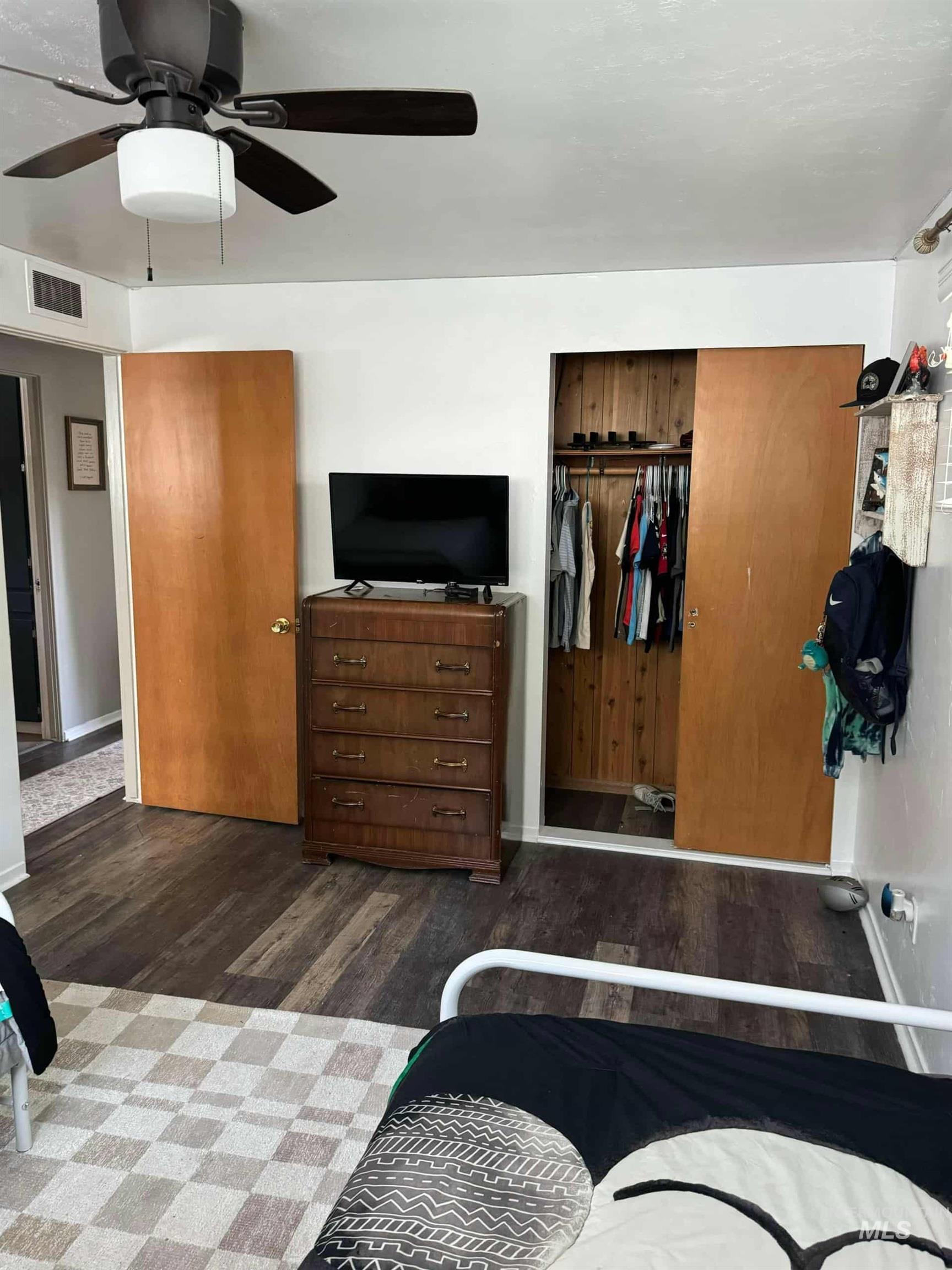 Bedroom with a closet, dark wood-style flooring, and a ceiling fan