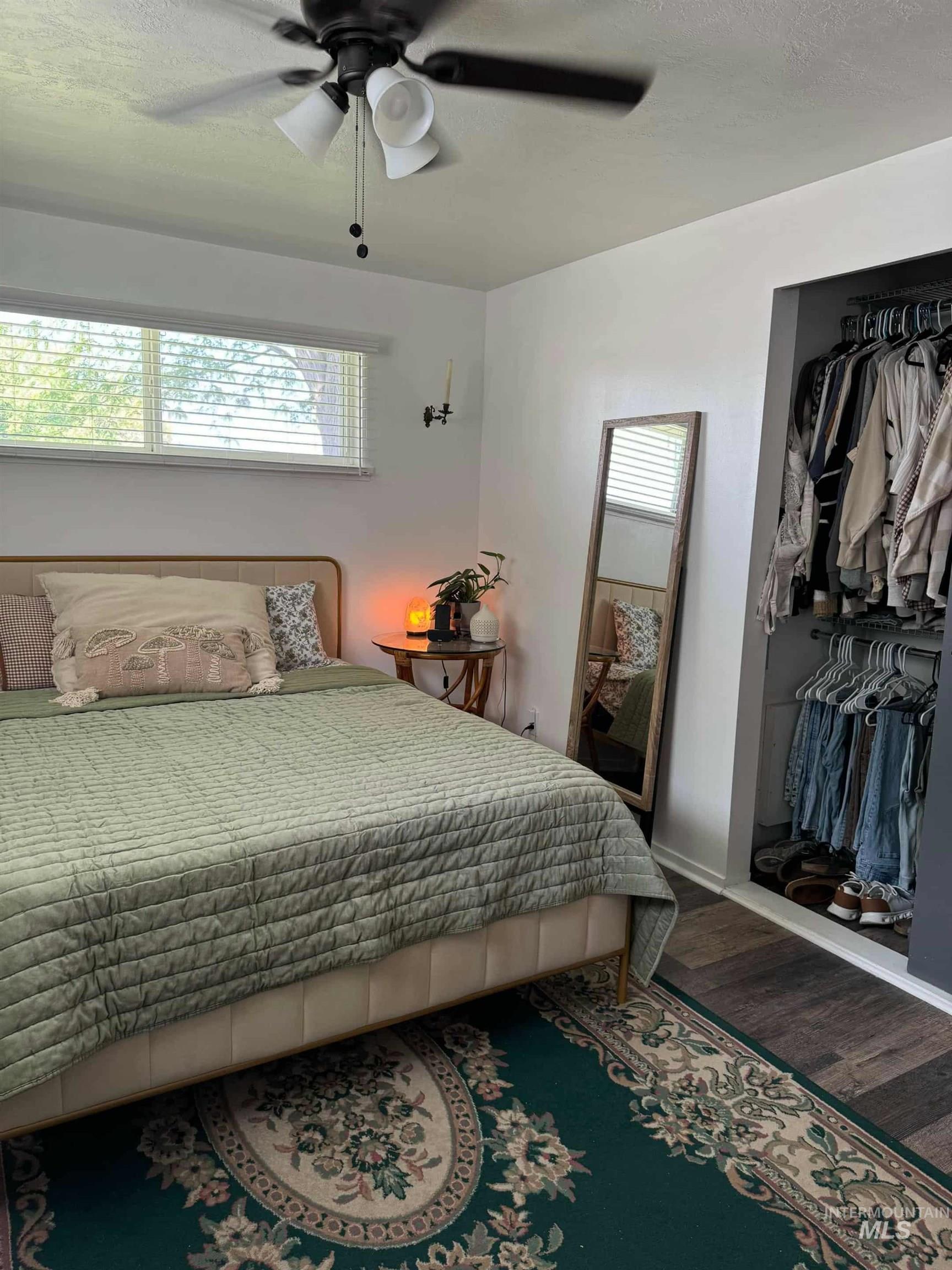 Bedroom featuring wood finished floors, multiple windows, a ceiling fan, and a textured ceiling