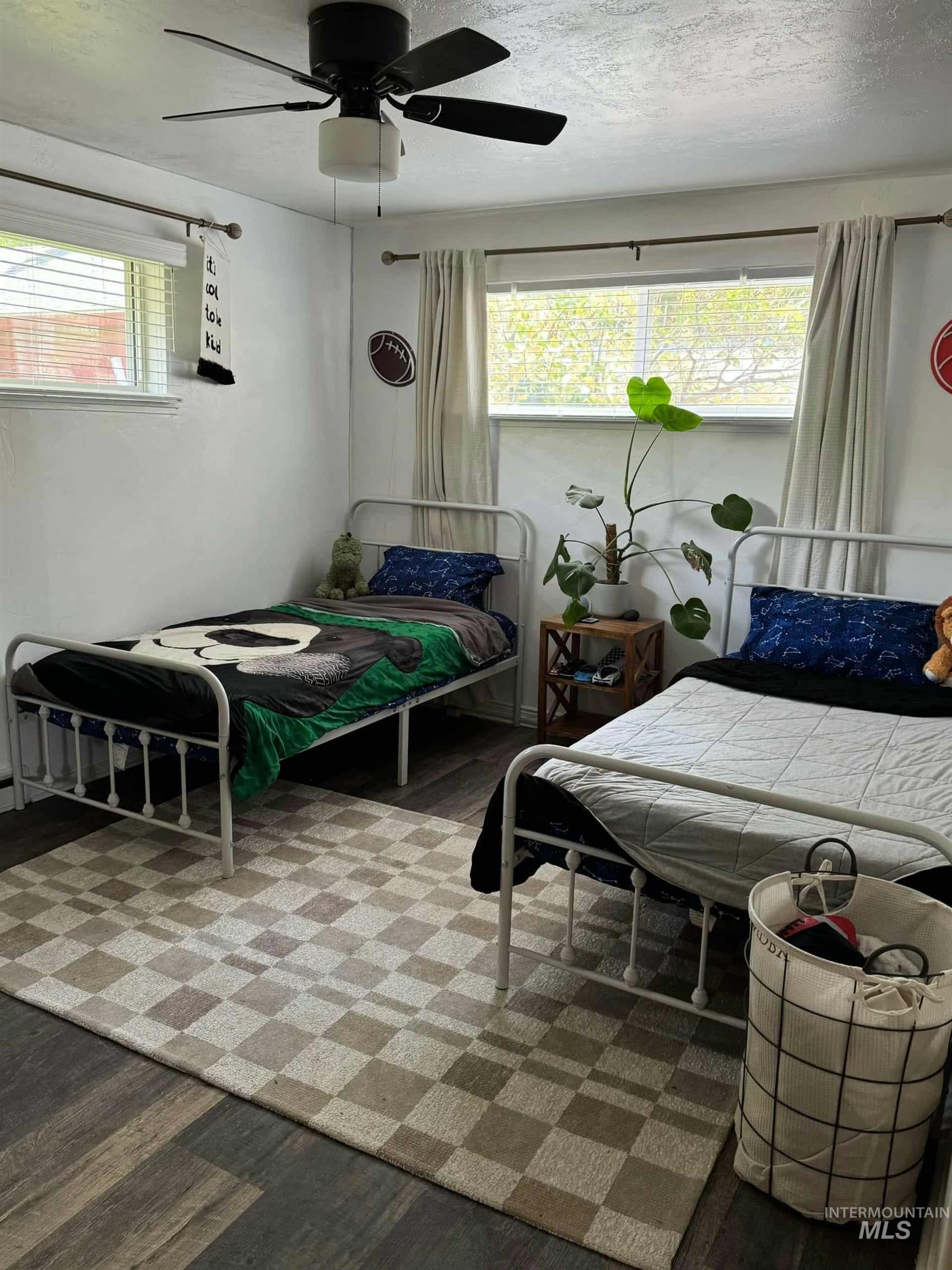 Bedroom with wood finished floors, a ceiling fan, and a textured ceiling