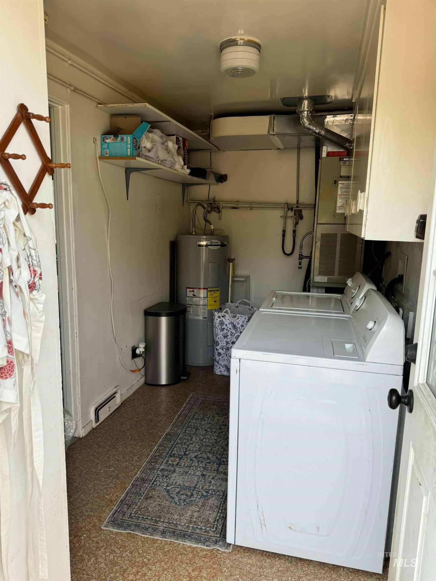 Washroom with independent washer and dryer, a baseboard radiator, and electric water heater