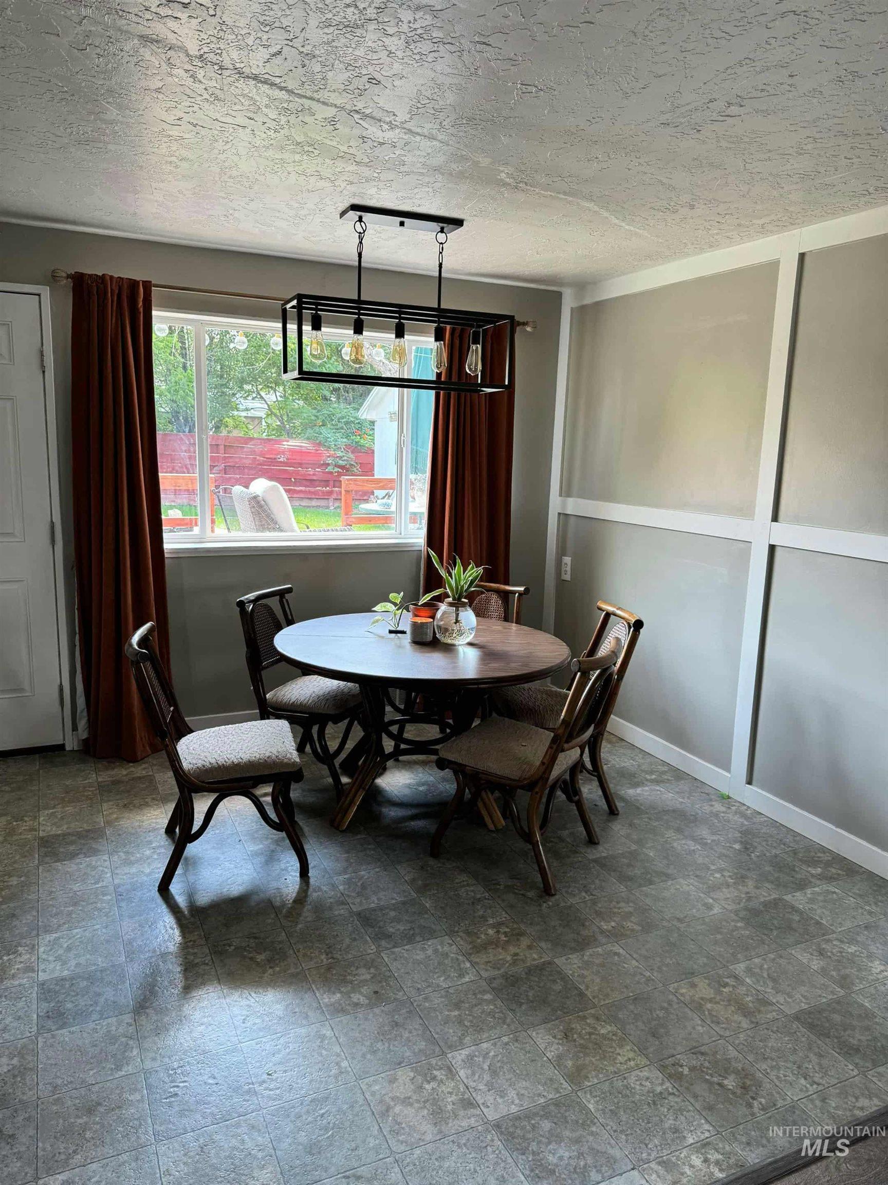 Dining space with a textured ceiling and stone finish floors