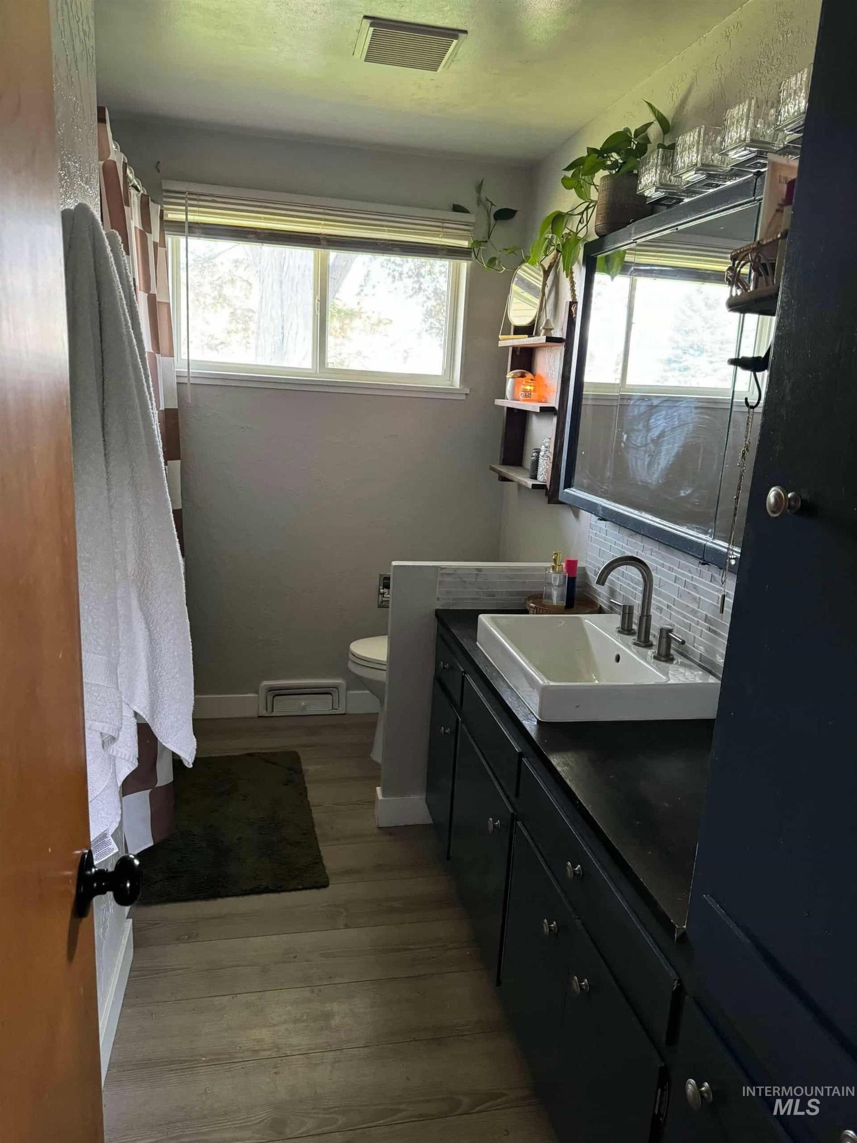 Bathroom with vanity, a shower with curtain, backsplash, and light wood-type flooring
