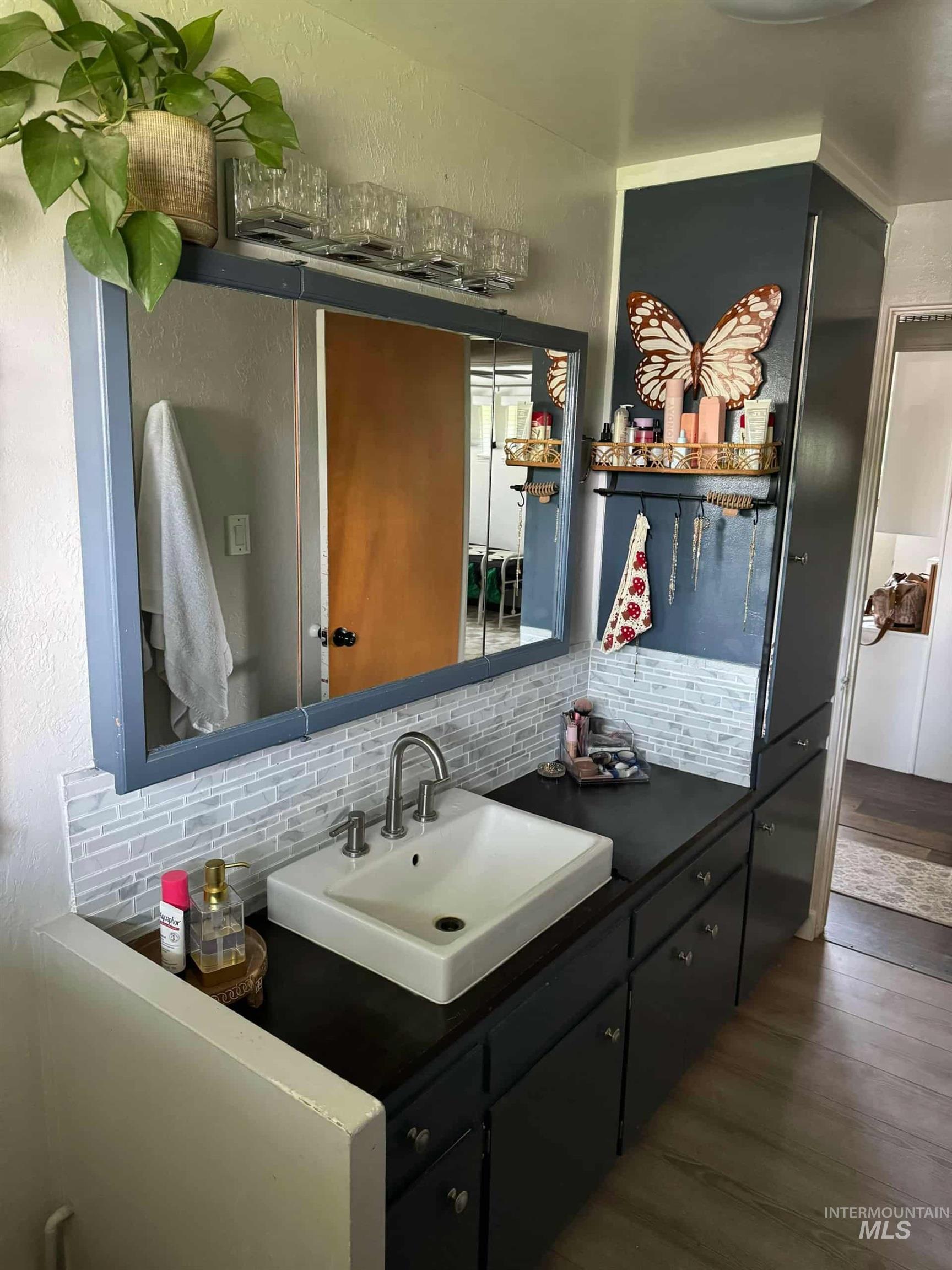 Bathroom with vanity, tasteful backsplash, a textured wall, and dark wood-style floors