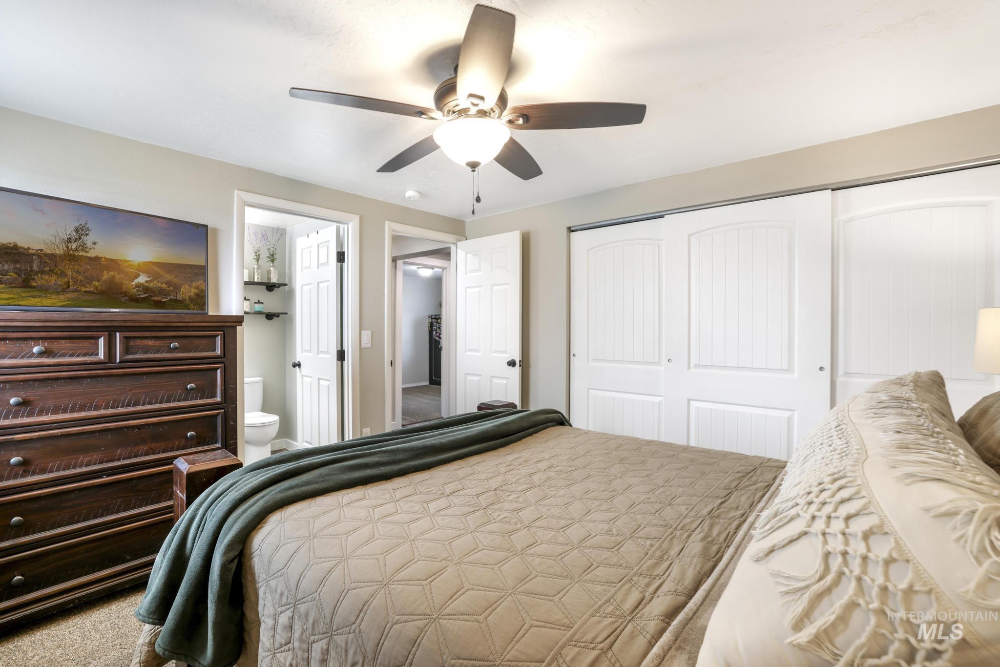 Carpeted bedroom with a closet, a ceiling fan, and ensuite bathroom