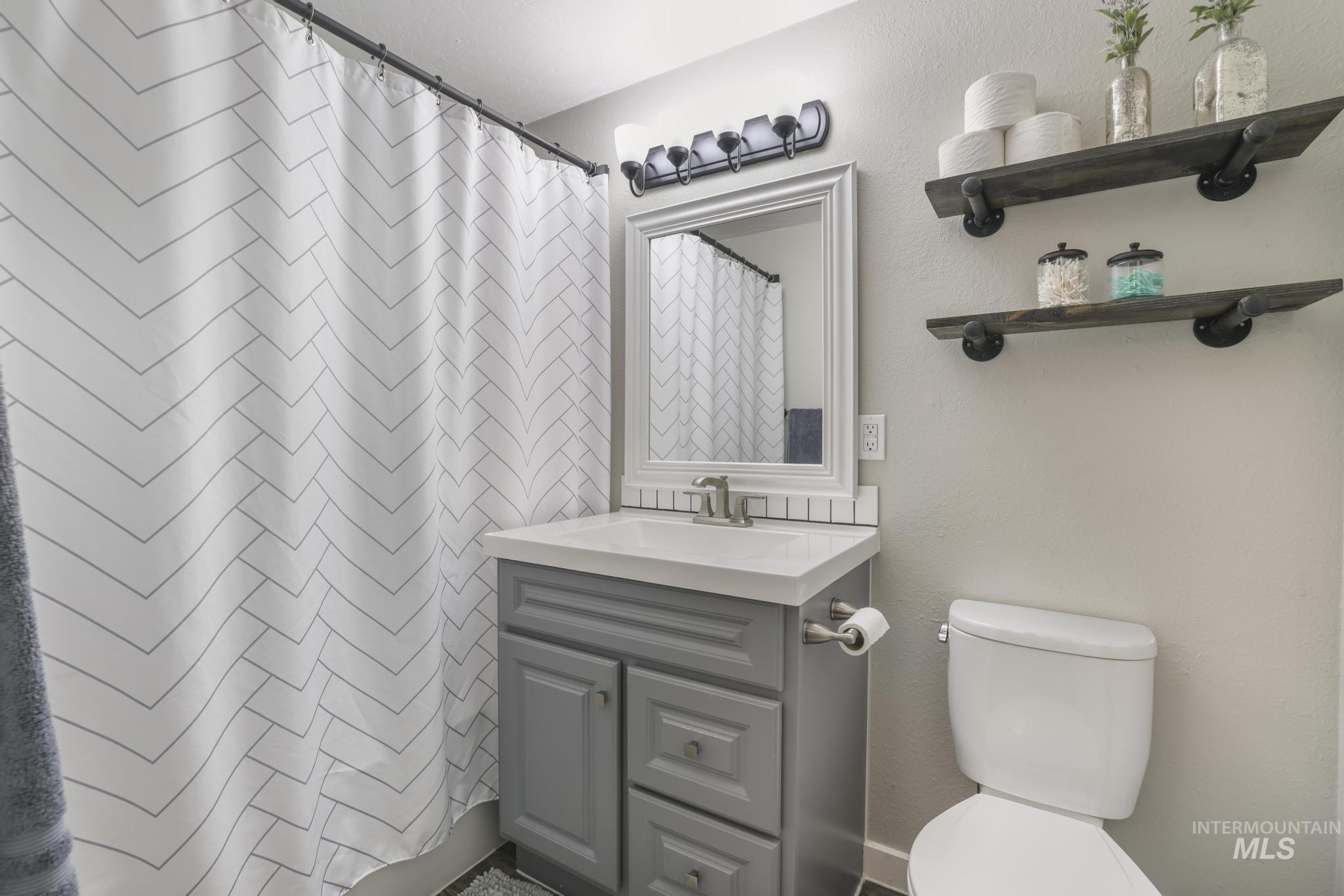 Full bath with curtained shower, vanity, and a textured wall