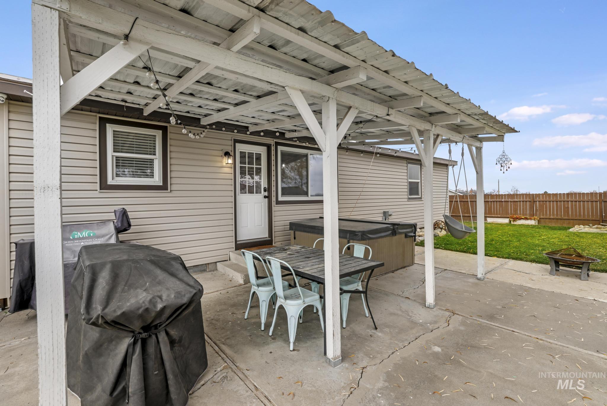 View of patio with a hot tub, a fire pit, area for grilling, and outdoor dining space