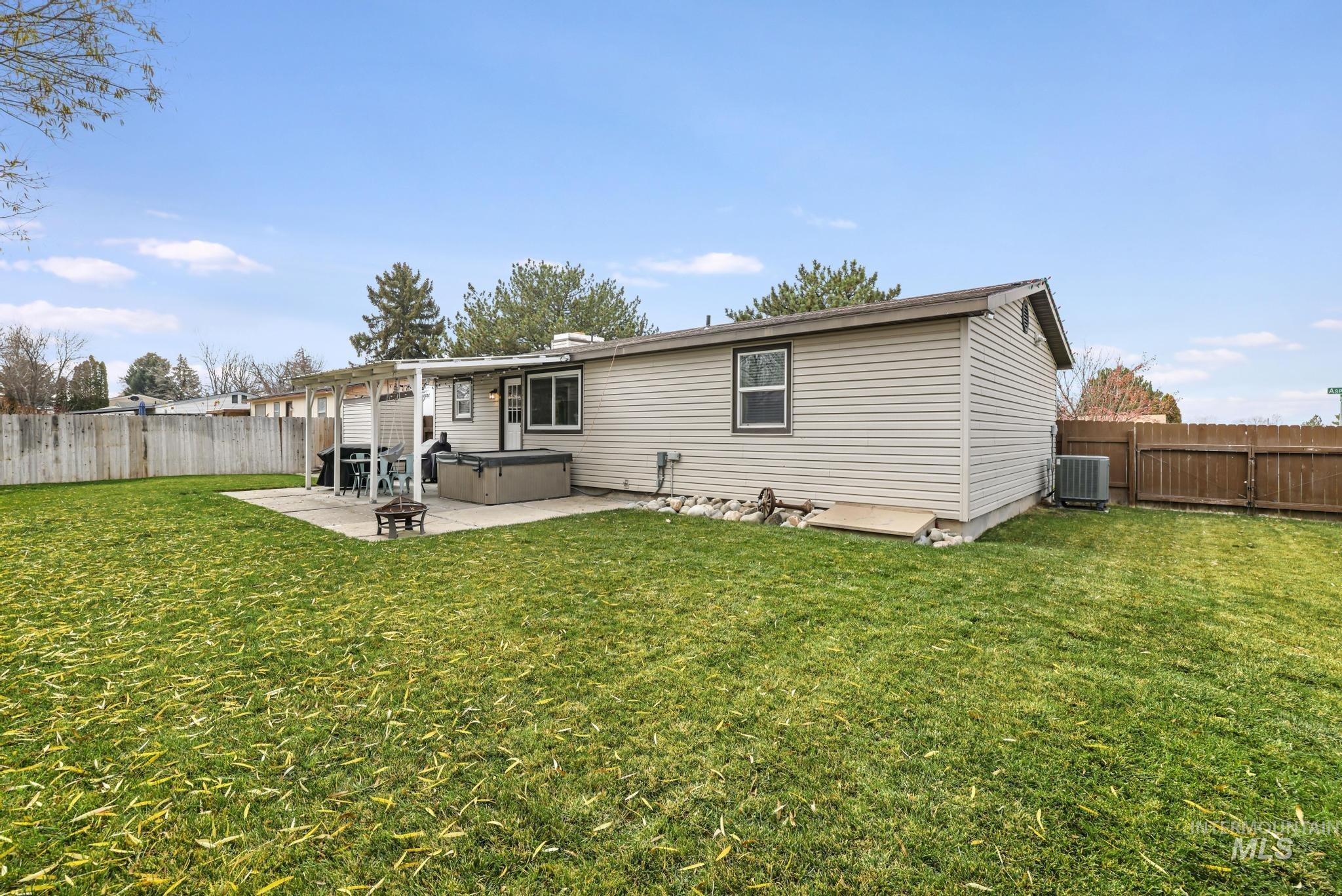 Back of property featuring a fenced backyard, a patio area, and a hot tub