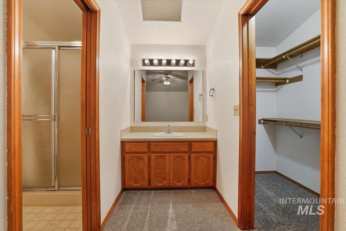 Full bathroom with a spacious closet, vanity, and a stall shower