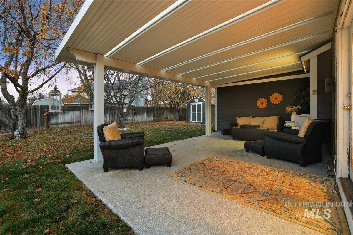 Fenced backyard with a patio area, an outdoor hangout area, and a shed