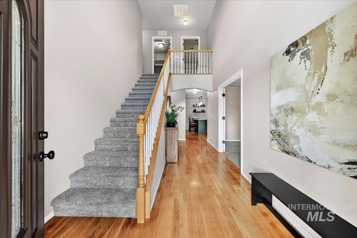 Staircase with a towering ceiling and wood finished floors