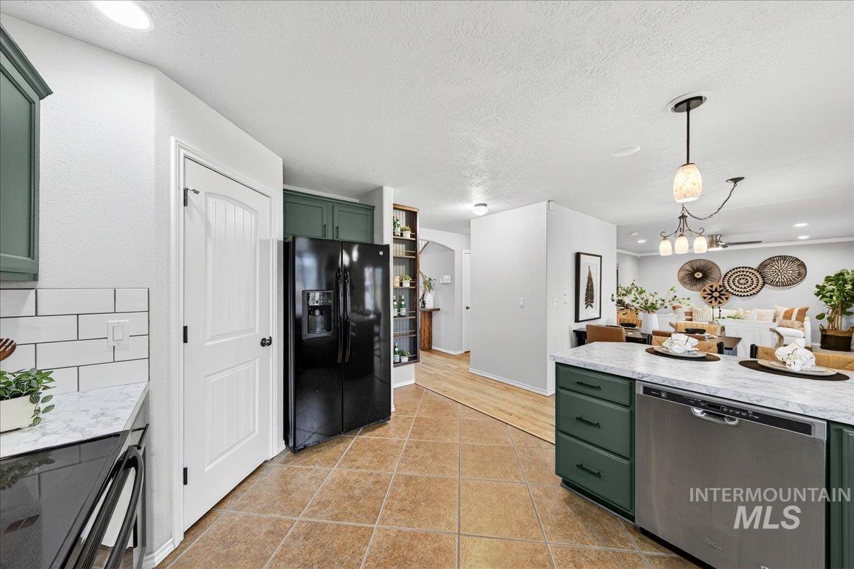 Kitchen with green cabinets, stainless steel dishwasher, black refrigerator with ice dispenser, electric range oven, and pendant lighting