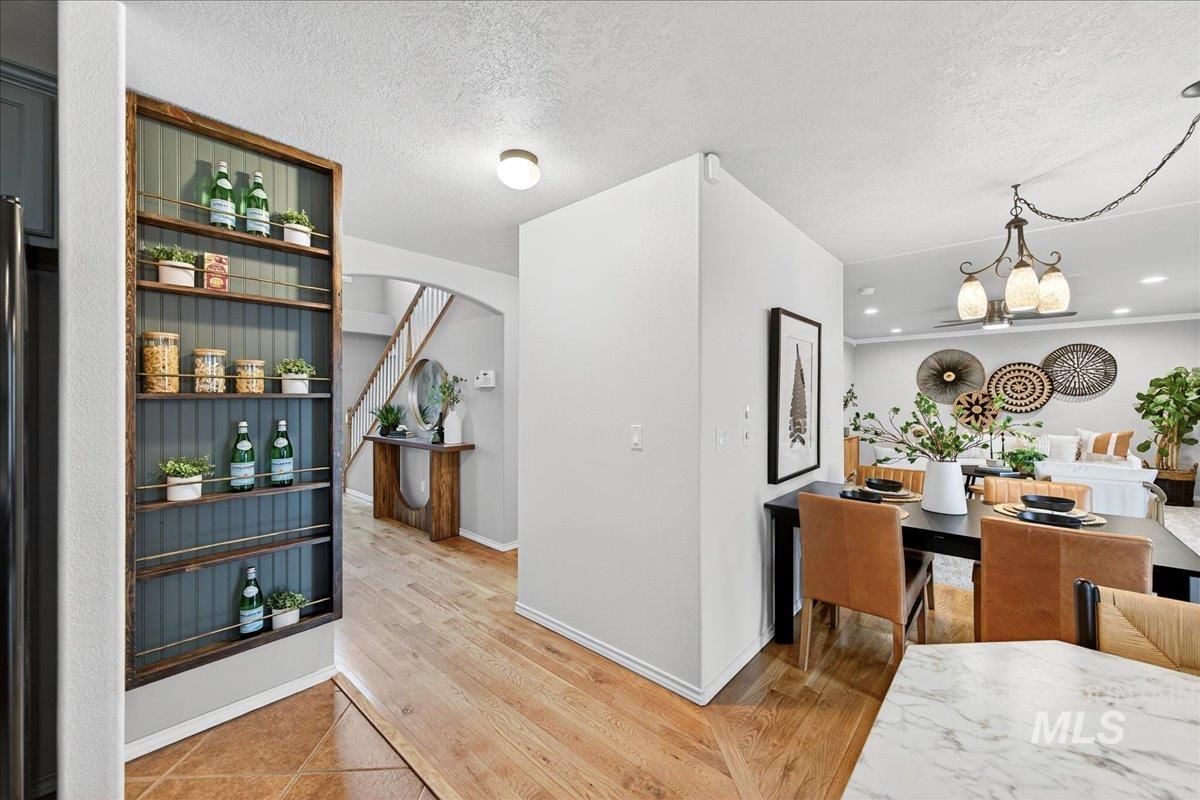 Dining room featuring arched walkways, light wood-type flooring, a textured ceiling, a chandelier, and recessed lighting