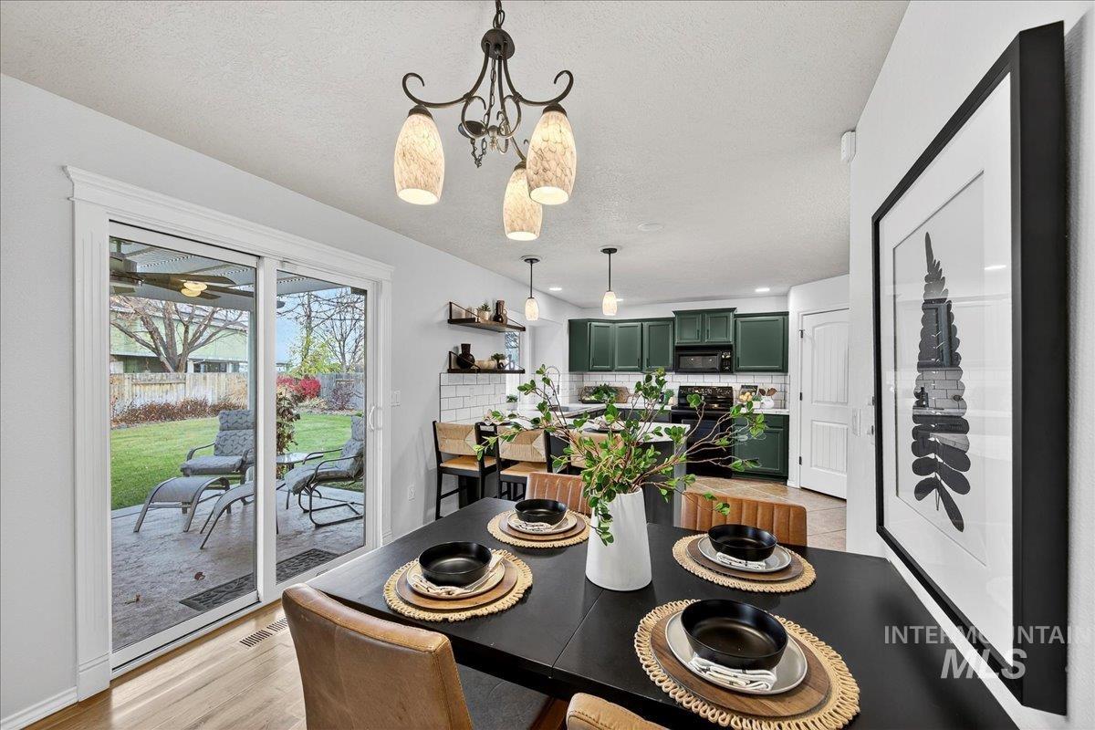 Dining room with light wood-style floors, a textured ceiling, and a chandelier