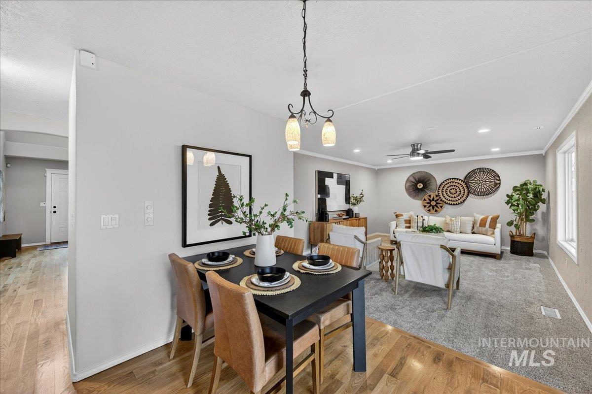 Dining area with light wood-style floors, ceiling fan, recessed lighting, crown molding, and a chandelier
